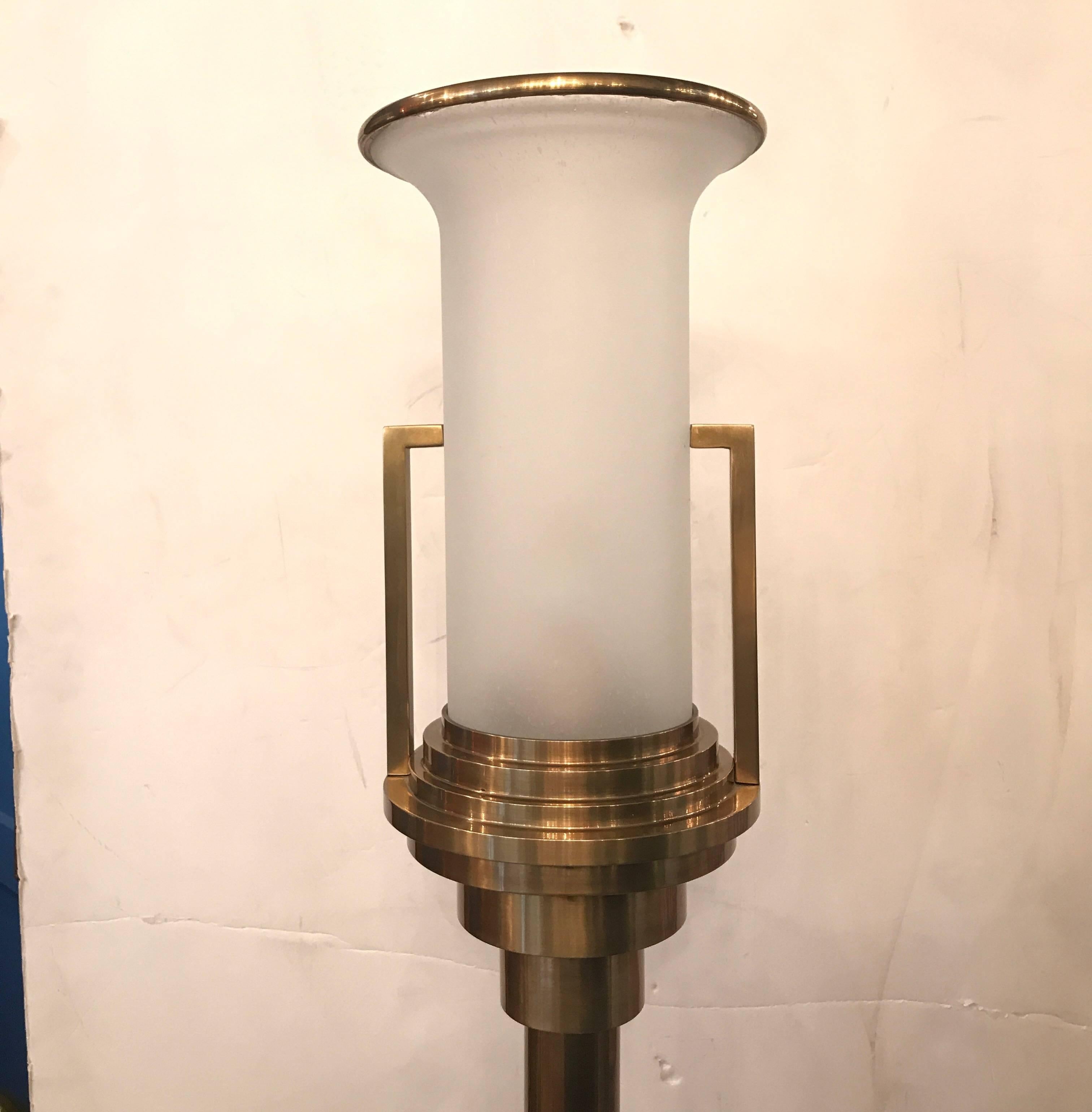 A pair of high style Italian burnished cast brass and opaque white class torchere floor lamps. Deco style with flared glass shades, stepped tops with handles and weighted bases.