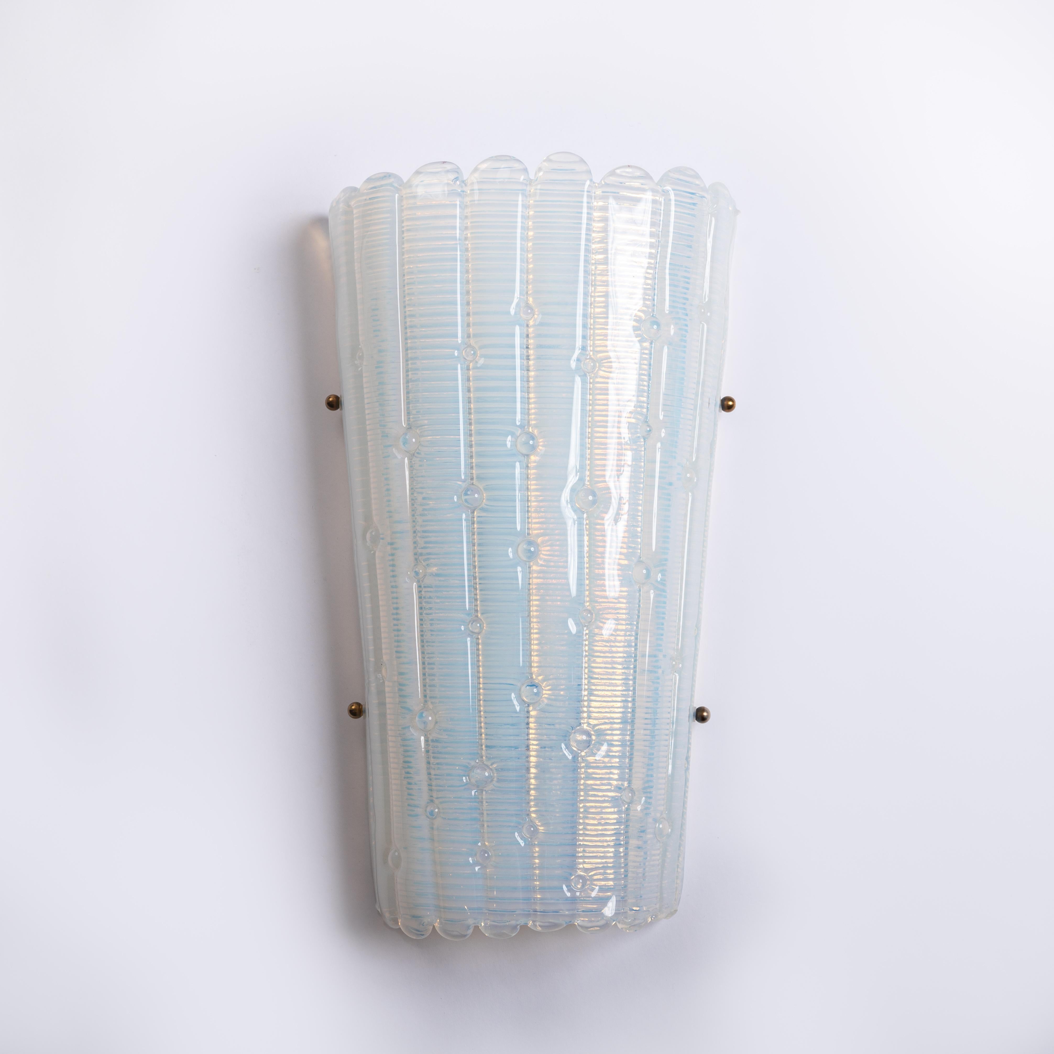 Modern, conical, Italian wall lamps in opalescent glass.
Flat bars lined up with small round decorations form the outer wall. 
The inside is completely finely ribbed and has an influence on the refraction of light.
Small brass balls decorate the end