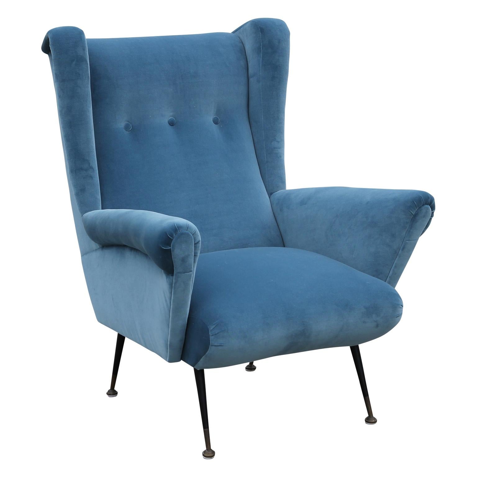 Wonderful pair of wingback lounge chairs made in Italy, circa 1950. Chairs are freshly upholstered in a soft blue velvet. Delicate black enameled legs are finished in patinated brass levellers. Stunning from all angles.