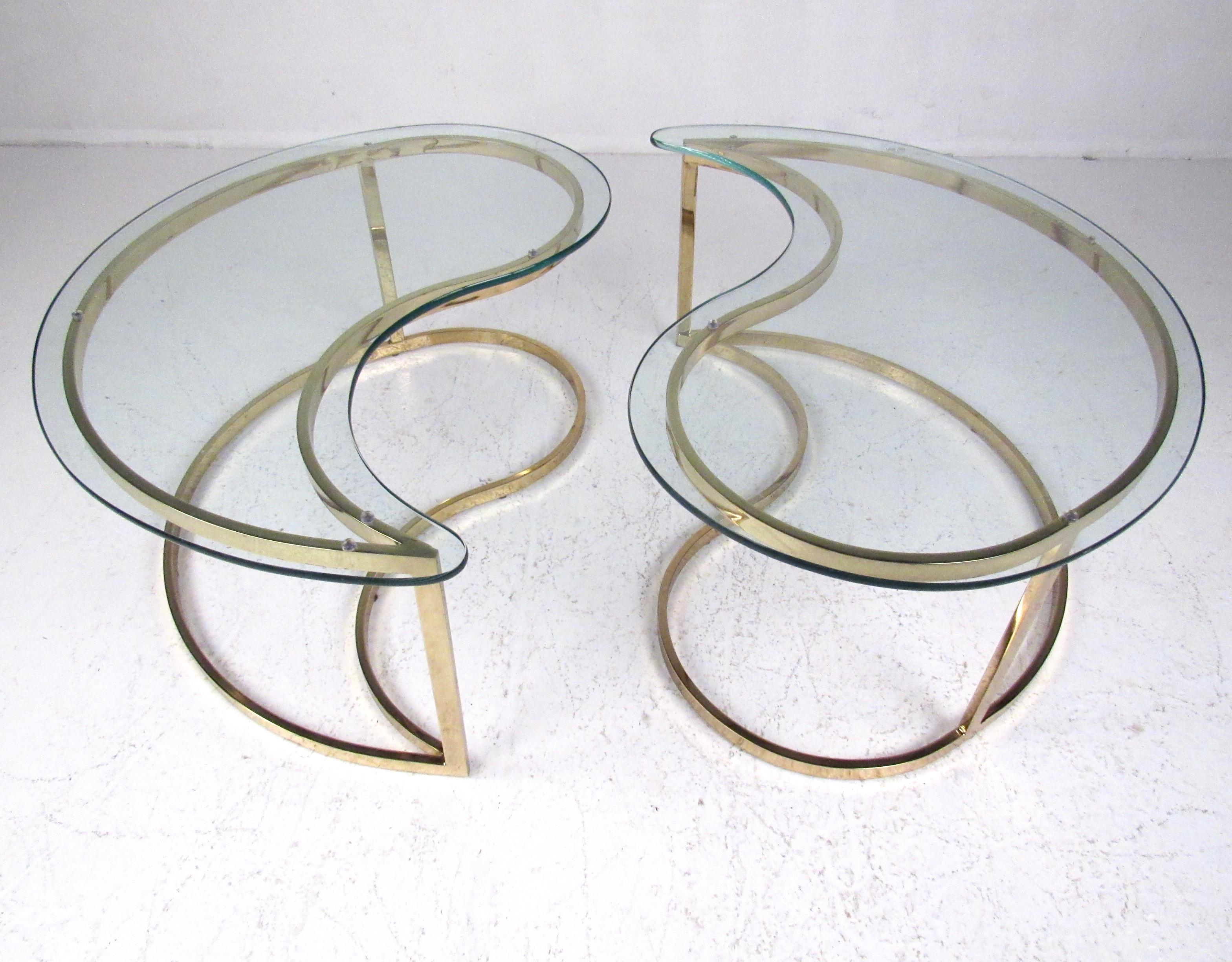 This pair of elegant modern end tables feature brass color finish and sculptural kidney shaped design. Thick glass tops make for perfect sofa end table or waiting room lamp table use. Please confirm item location (NY or NJ).