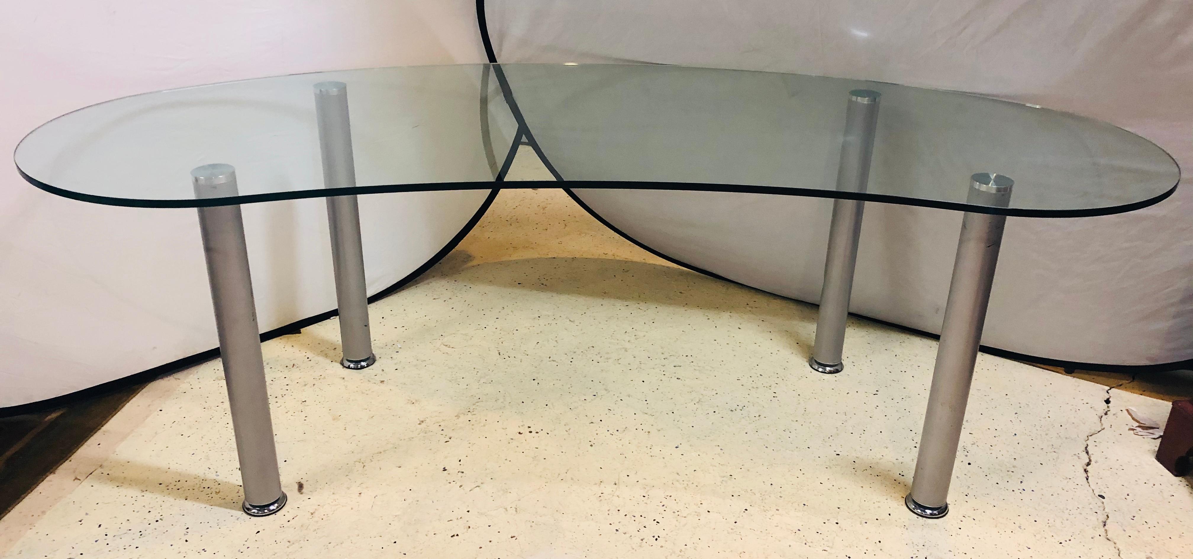 Pair of modern kidney shaped glass top desk on steel legs. This fine pair of modern desk have a large and impressive kidney shaped glass top supported by polished chrome and steel table legs. Can purchase one or the pair as you have the need. Great