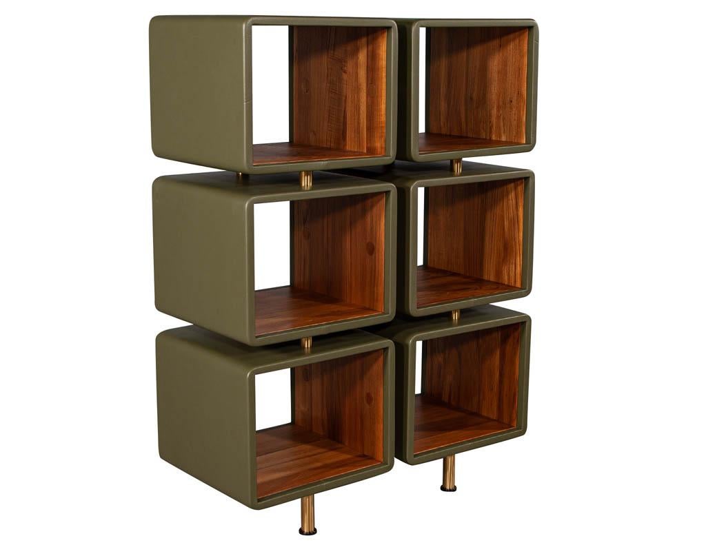 Pair of modern leather Clad bookcases. Olive leather clad bookshelves with teak interior and satin brass accents.

Price includes complimentary curb side delivery to the continental USA.

Measurement of interior cube
W: 17.5”, H: 14”, D:17.5”.