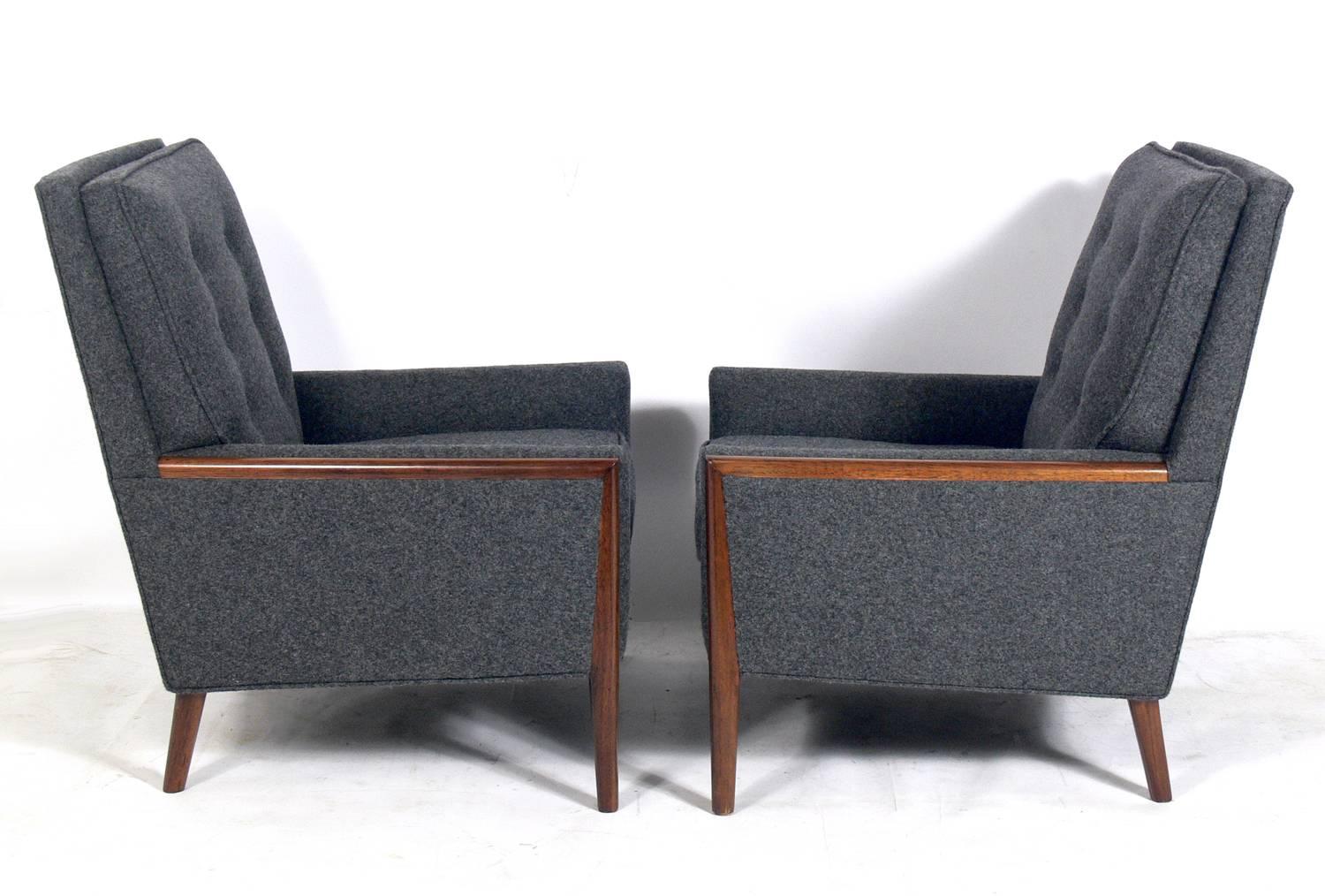 Pair of modern lounge chairs, in the style of T.H. Robsjohn-Gibbings, American, circa 1960s. They have been reupholstered in a charcoal gray upholstery and the walnut trim has been cleaned and oiled.