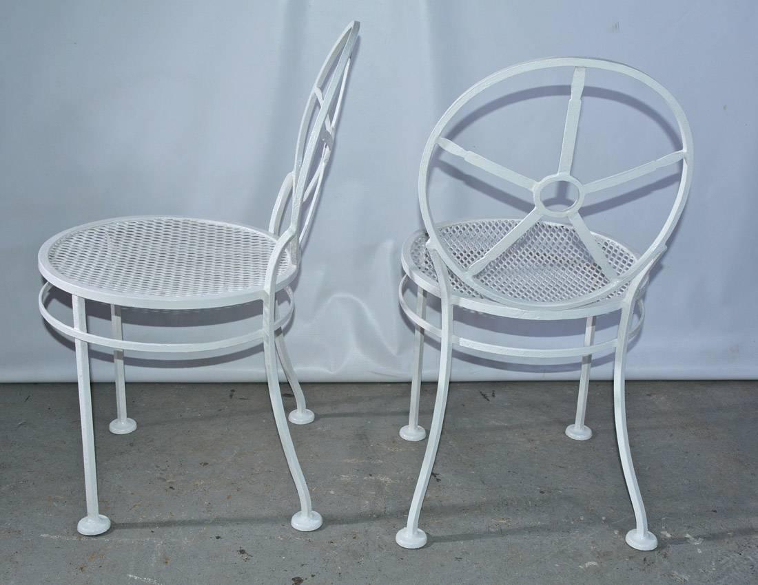 The pair of modern metal porch/garden dining chairs have circular backs divided into pie-shaped sections, mesh seats and an additional ring attached to the footed legs for sturdy support. The chairs are painted white.
Measure: Seat height 17