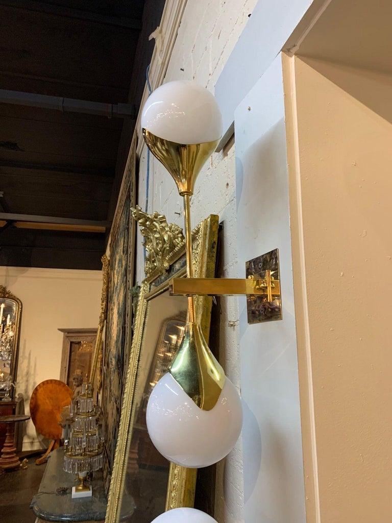 Very sleek set of modern gilt brass and Murano glass sconces. Each sconce has 2 glass balls on a shining brass base. A lovely choice for a contemporary setting.