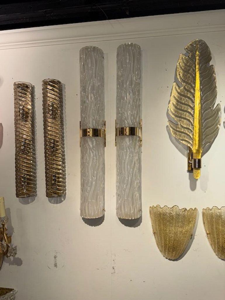 Un par de modernos apliques de barril de cristal de Murano texturizado con detalles de latón. Estos apliques de estilo italiano añaden un toque de elegancia a cualquier espacio con su diseño único y sus materiales de alta calidad. Perfecto para