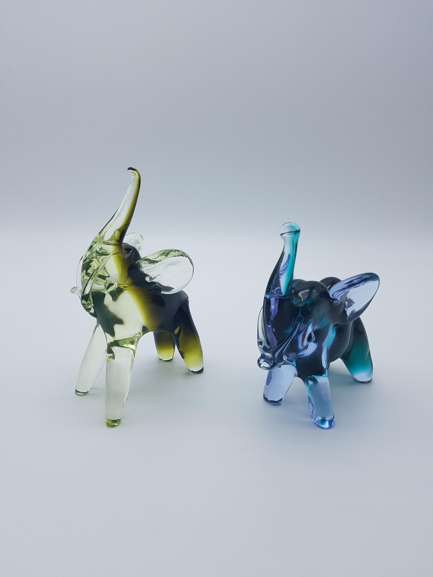 Pair of cute Murano glass elephants handmade by Gino Cenedese e Figlio in the late 1970s. One elephant is made in lavdner and green color, while the pther is yellow and military green, a color scheme quite popular in the 1970s. Both elephants are