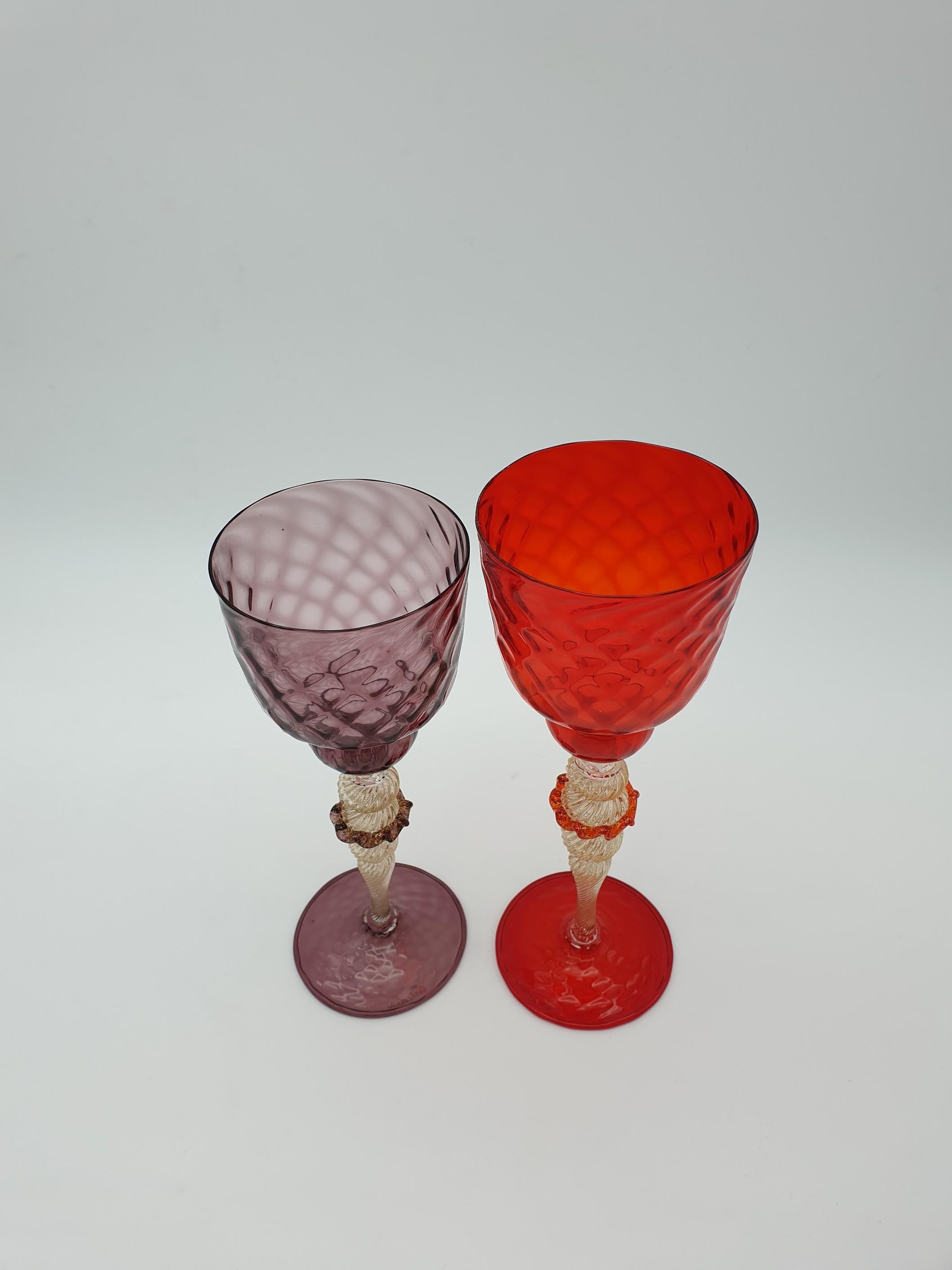 Pair of modern Murano glass goblets, completely handmade and mouth-blown by Gino Cenedese e Figlio glass factory in the late 1990s. This striking set is made of two similar goblets, one in amethyst and the other in red color. Both goblets feature a