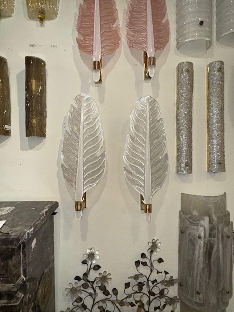 Ce listing présente une paire d'appliques modernes en verre de Murano en forme de feuille, givrées dans une finition blanc perle. Les appliques sont fabriquées à partir de verre magnifique, ce qui leur confère un aspect luxueux et élégant. Le design
