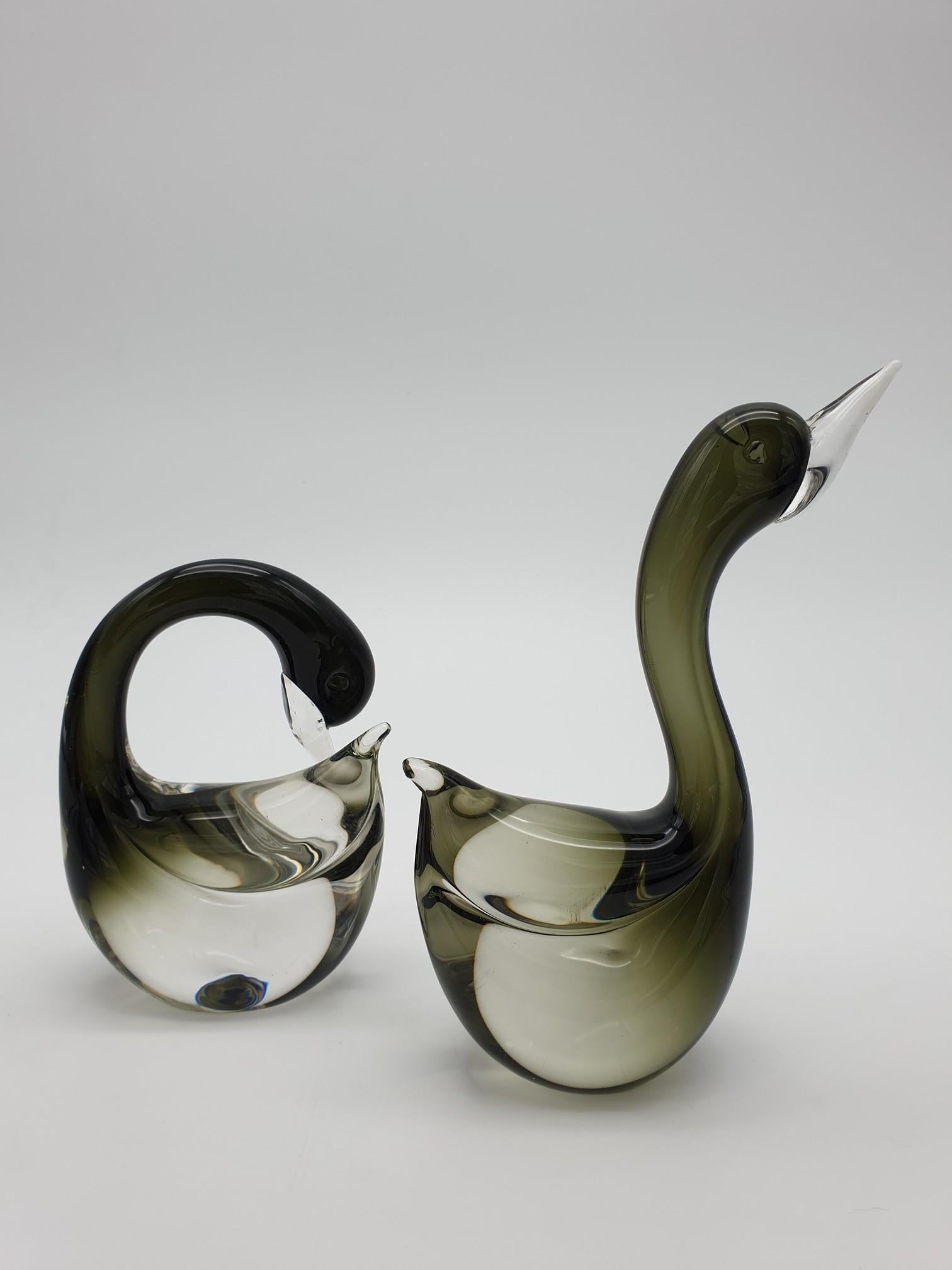 Pair of small Murano glass swans, manufactured at the famous glass-factory Gino Cenedese e Figlio from the 1960s throughout the 1990s. These glass swans have been completely handmade, in clear glass with splashes of black color. These wonderful