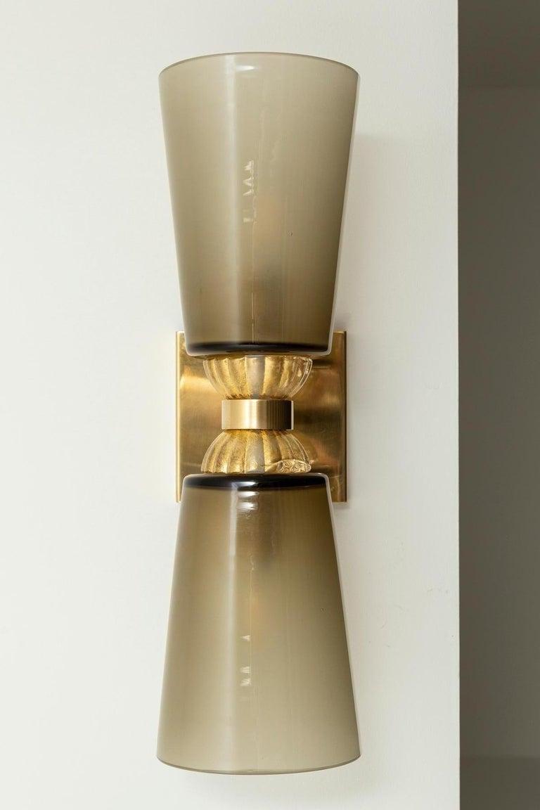 A beautiful pair of greige cone shaped cups fused with gold glass an upheld with solid unlacquered brass arms connecting to a square shaped canopy.

May be installed either horizontally or vertically.

These have great proportion and are equally