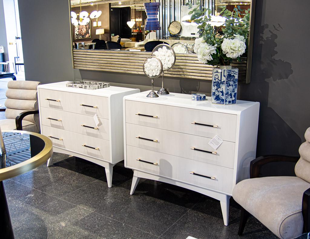 Introducing the perfect addition to your modern bedroom decor - a pair of stunning nightstand chests of drawers. These stylish cabinets feature a sleek satin white lacquer finish that exudes sophistication and elegance. The warm 2 tone drawer fronts