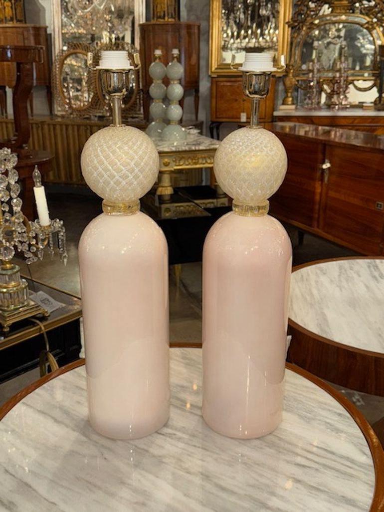 This product is a pair of modern Murano glass lamps featuring a beautiful combination of pale pink and gold colors. The unique design and craftsmanship of these lamps make them a stylish and elegant addition to any room. These lamps are sure to