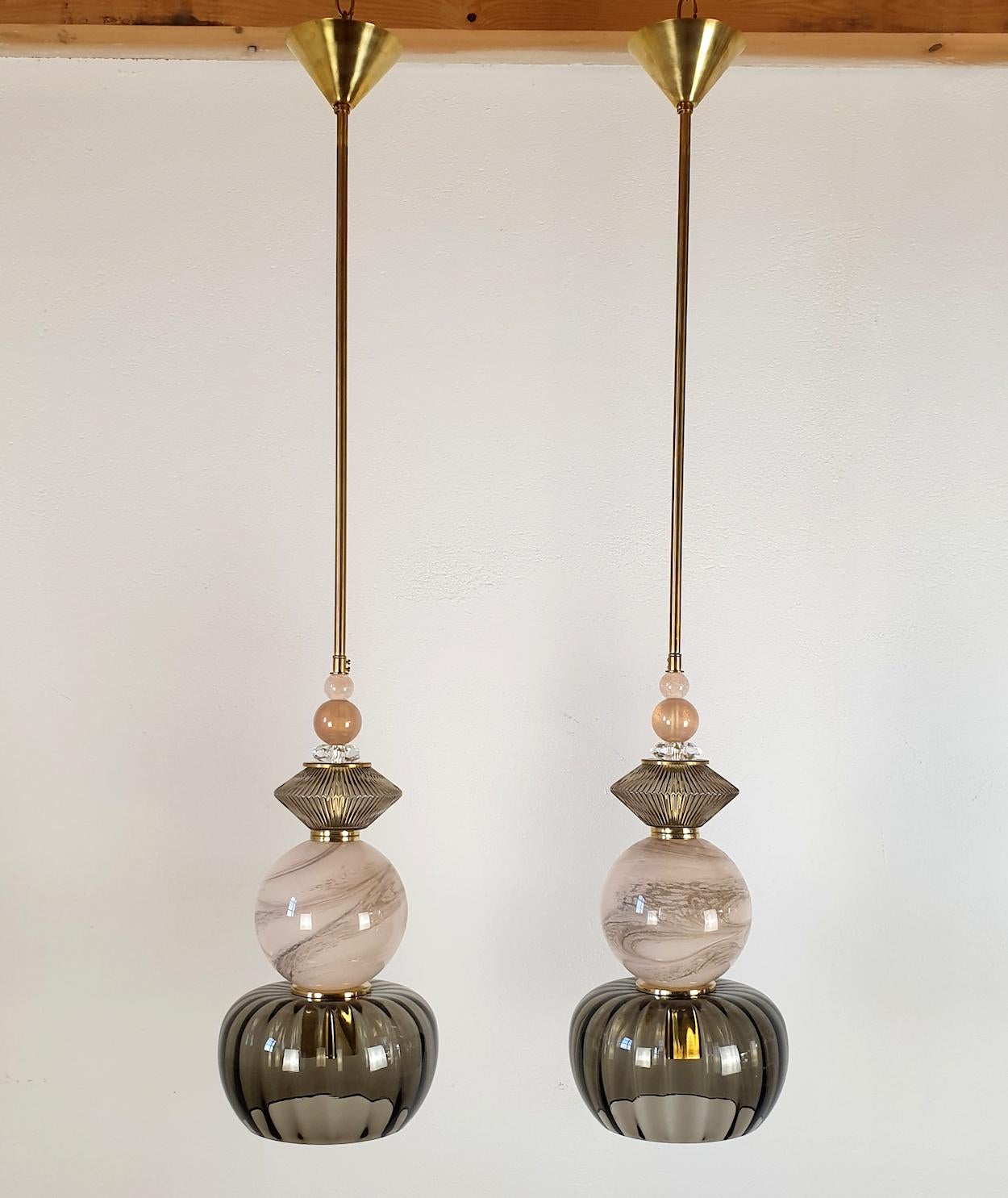 Pair of Murano glass and brass pendant ceiling lights, Italy 2000s.
Their quality and style make them look like pieces of jewelry.
The pair has a Mid-Century Modern style and is very trendy.
The pendants are made of a central soft pink translucent,