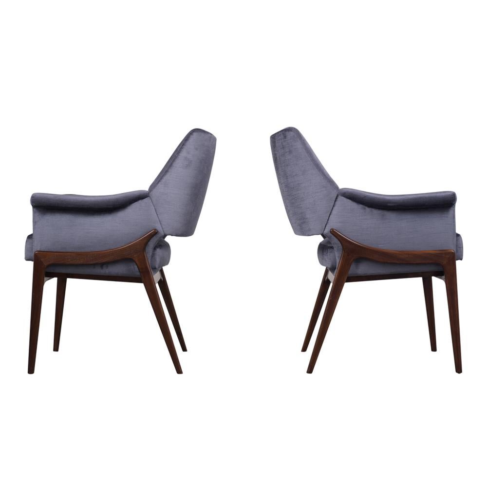 This pair of 1960s Mid-Century Modern style lounge chairs have been completely restored with new upholstery in a rich dark blue color velvet fabrics. The chairs feature a sleek rosewood base that compliments the coil spring comfortable seats. This