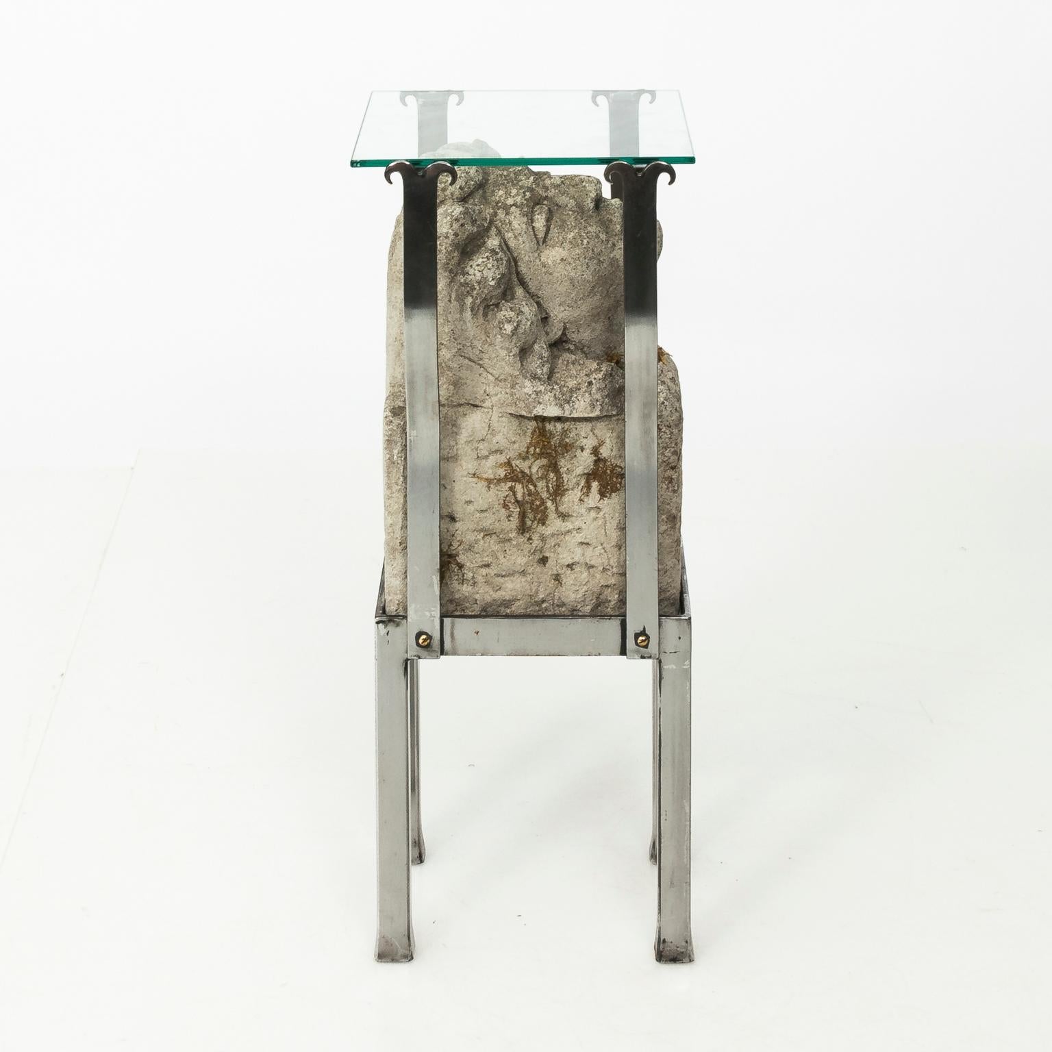 Contemporary set of two steel and glass side tables with carved stone head bases. These carved stone heads can be traced to a circa 1860 Victorian stable in Derbyshire, England.
   
