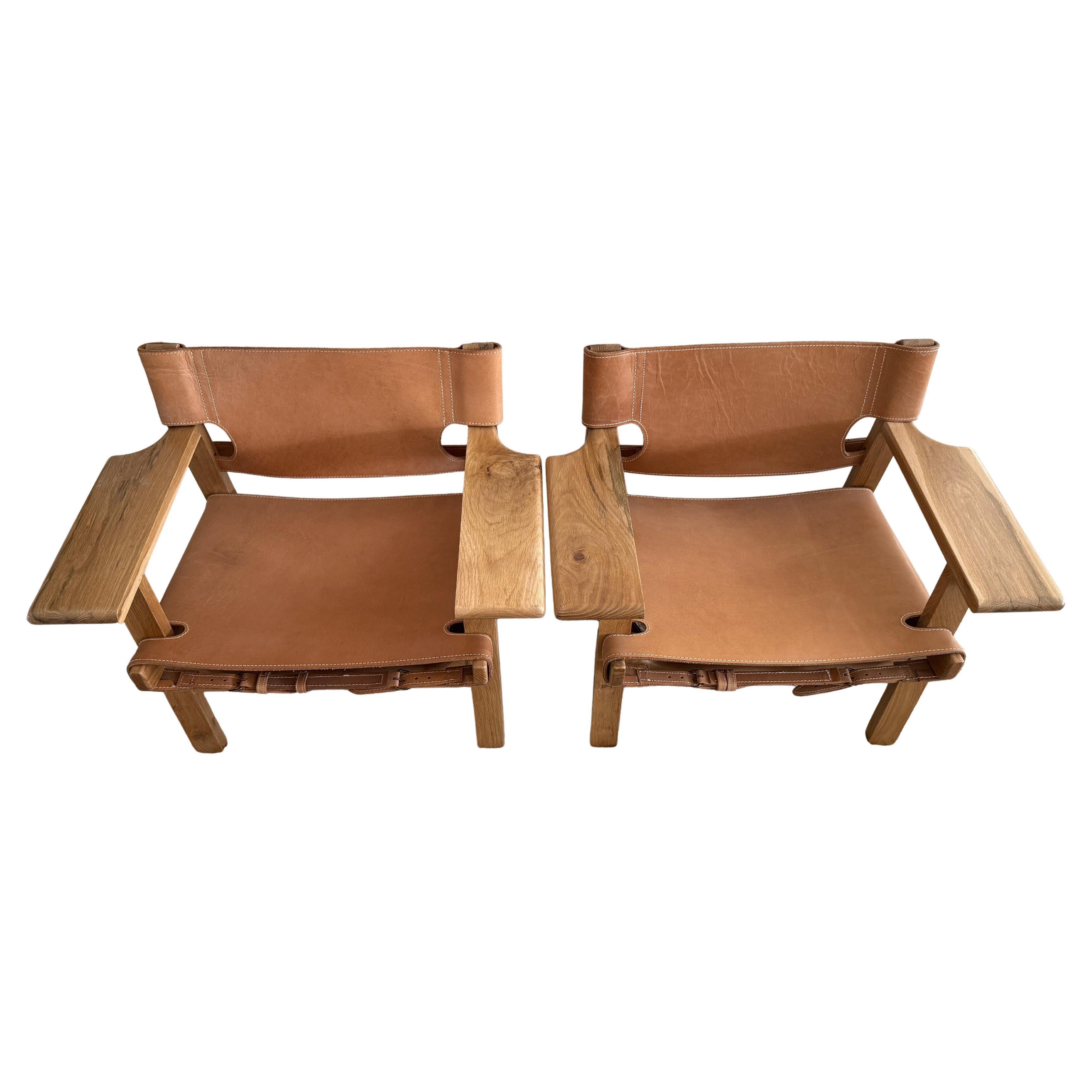 Paire de fauteuils de salon modernes en cuir à écharpe basse de style espagnol dans le style de Børge Mogensen. Cuir épais de couleur havane, surpiqûres blanches et boucles en laiton, cadres en bois de chêne clair massif. Peu ou pas d'usure, chaises