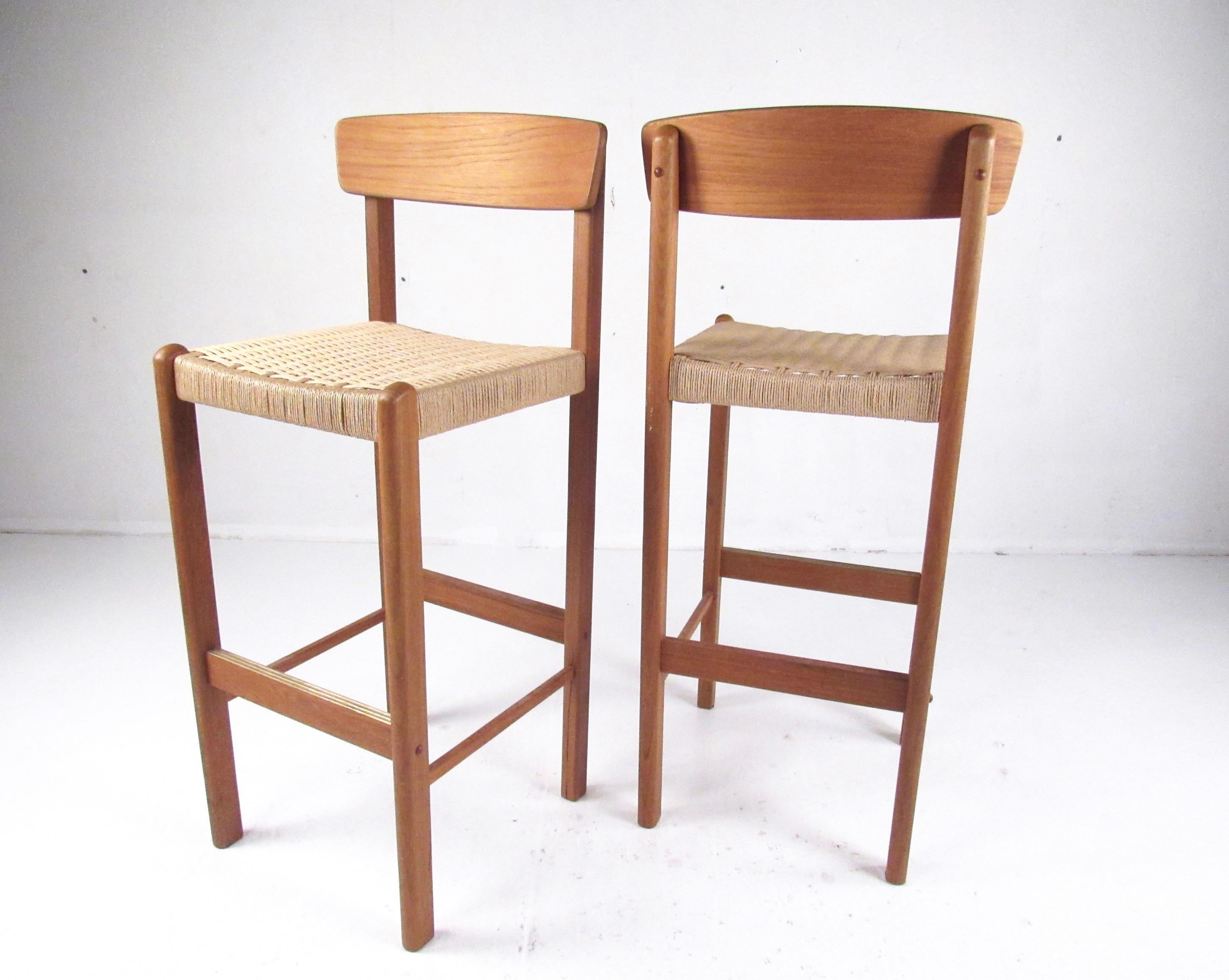 This beautiful pair of modern teak bar stools features Scandinavian style design, sturdy construction, and a stylish mix of hardwood and paper cord. An elegant midcentury style addition to home or business bar or counter seating arrangement. Please
