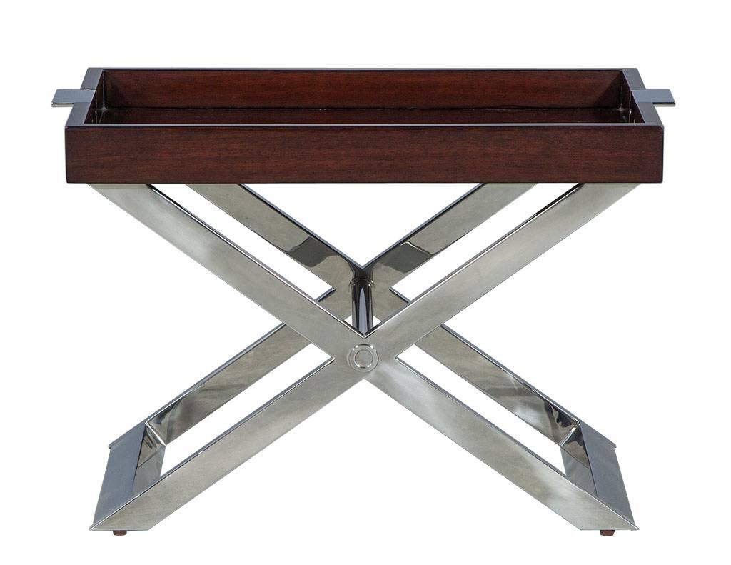 Pair of modern tray tables by Ralph Lauren. With removable serving tray tops and a stainless steel X-base it is a perfect blend of functionality and beauty.  The tray handles are finished in dark cherry, adding a last pop of contrast to the piece. A