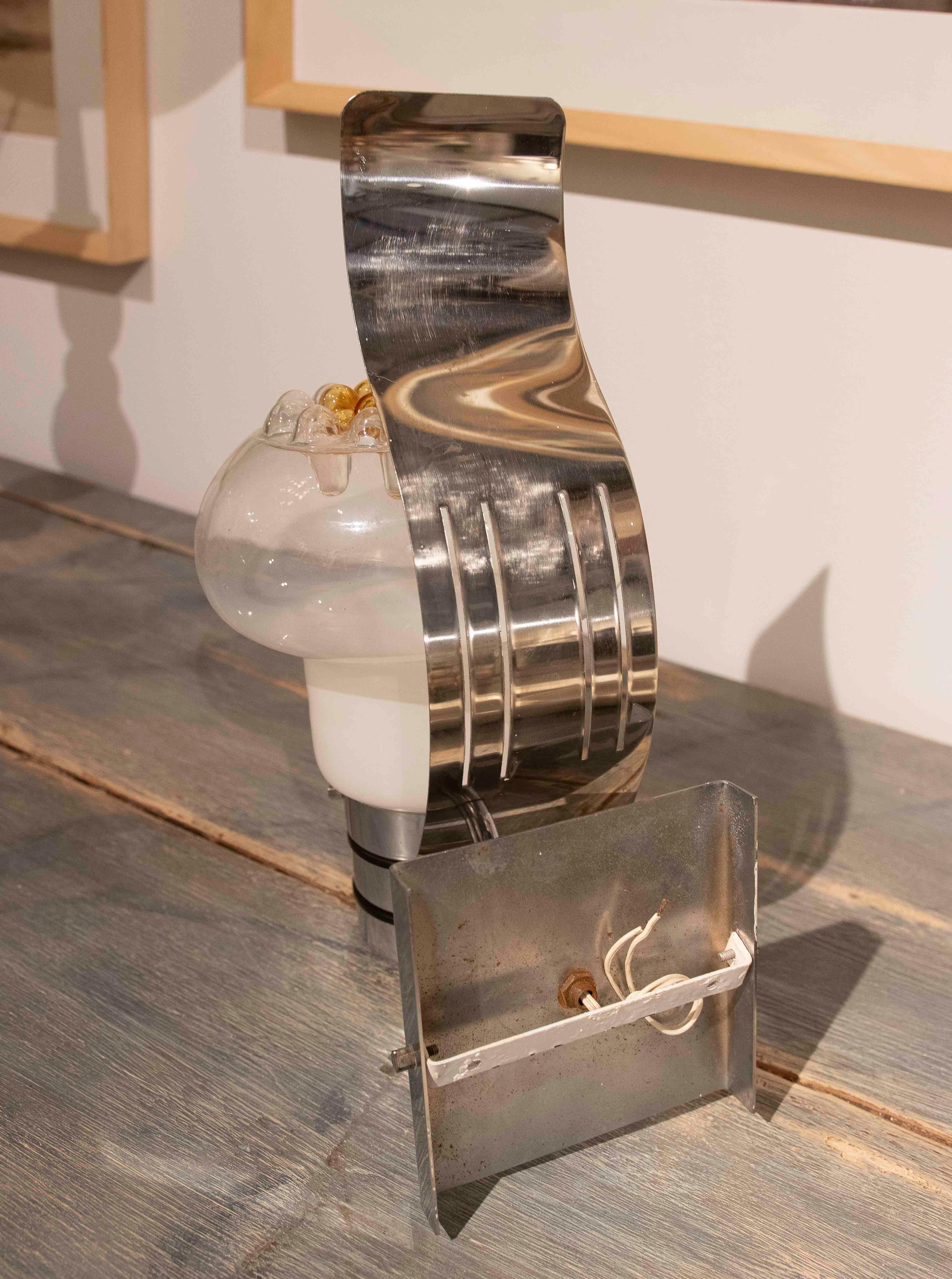 Set di appliques con struttura in metallo cromato e paralume in vetro decorativo. I pezzi combinano un design contemporaneo con dettagli unici, come le gocce color ambra che adornano la parte superiore del bicchiere. Perfetto per aggiungere un tocco