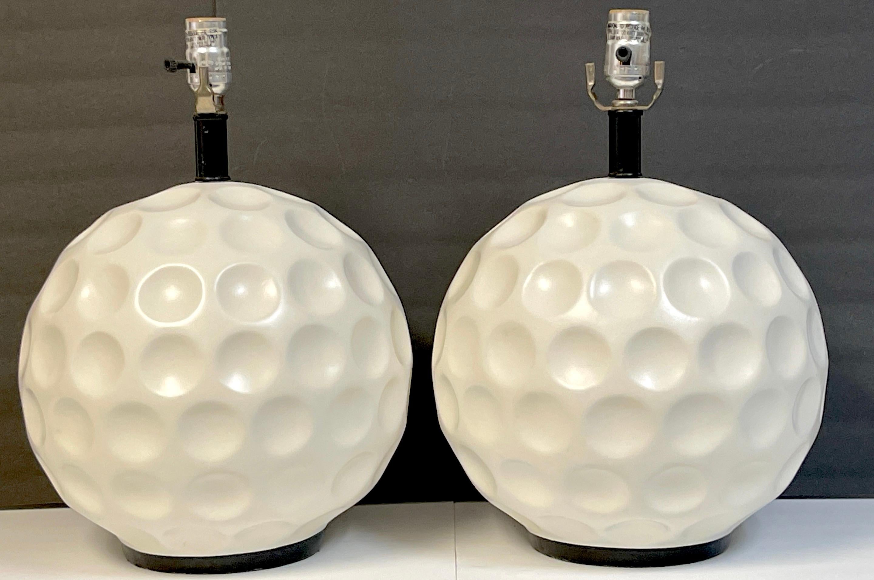 Pair of Modern White Enameled Metal 'Golf Ball' Lamps 
USA, Circa 1980s

A unique pair of large (each one has twelve -Inch diameter ) golf ball table lamps. Each one well made of forged/ cast metal, lacquered in white enamel. Raised on subtle