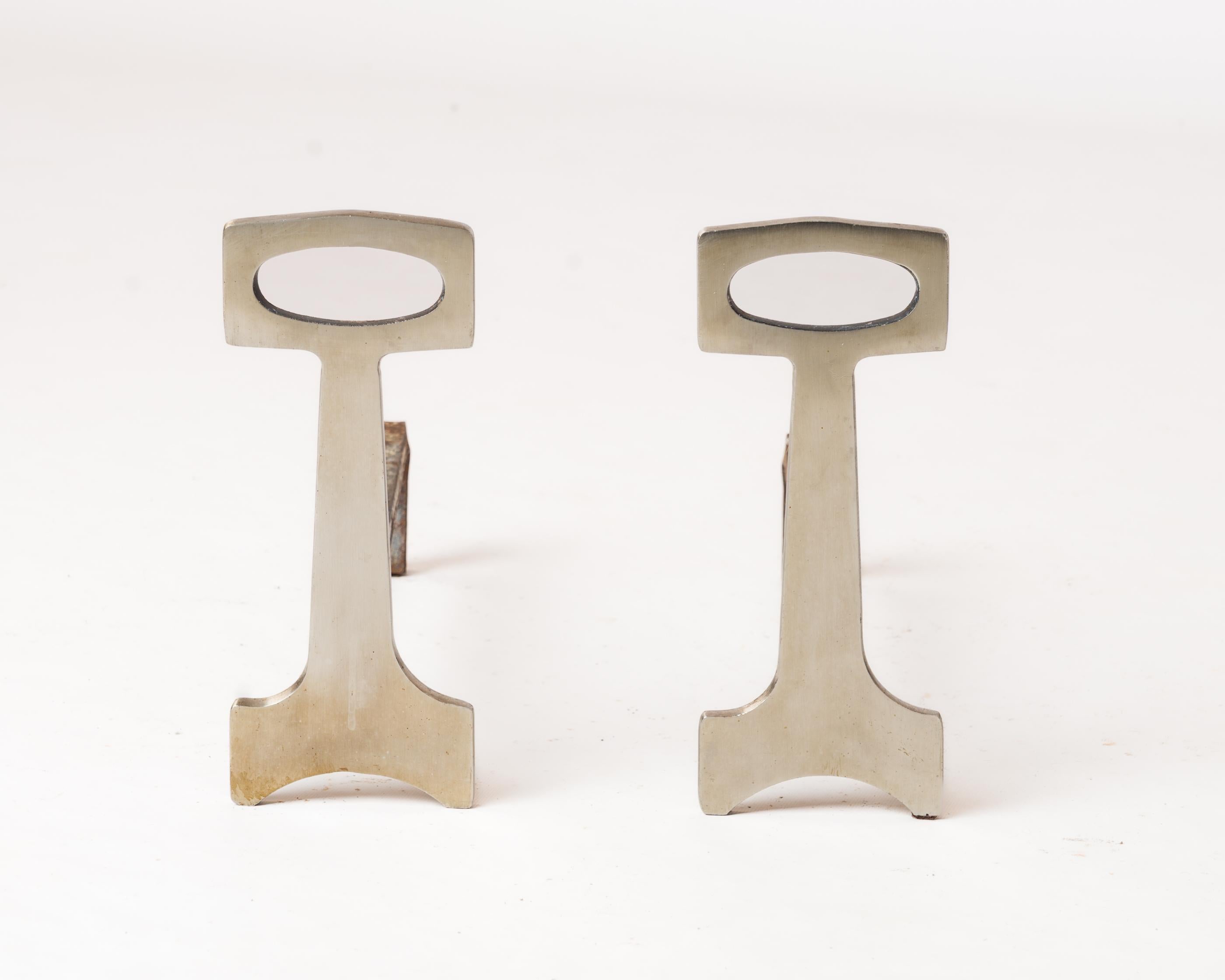 Pair of chic modernist andirons with polished steel finish. In fair vintage condition. 
These andirons will ship from France and can be returned to either France or to an upstate NY facility. Price includes shipping to the US except for possible