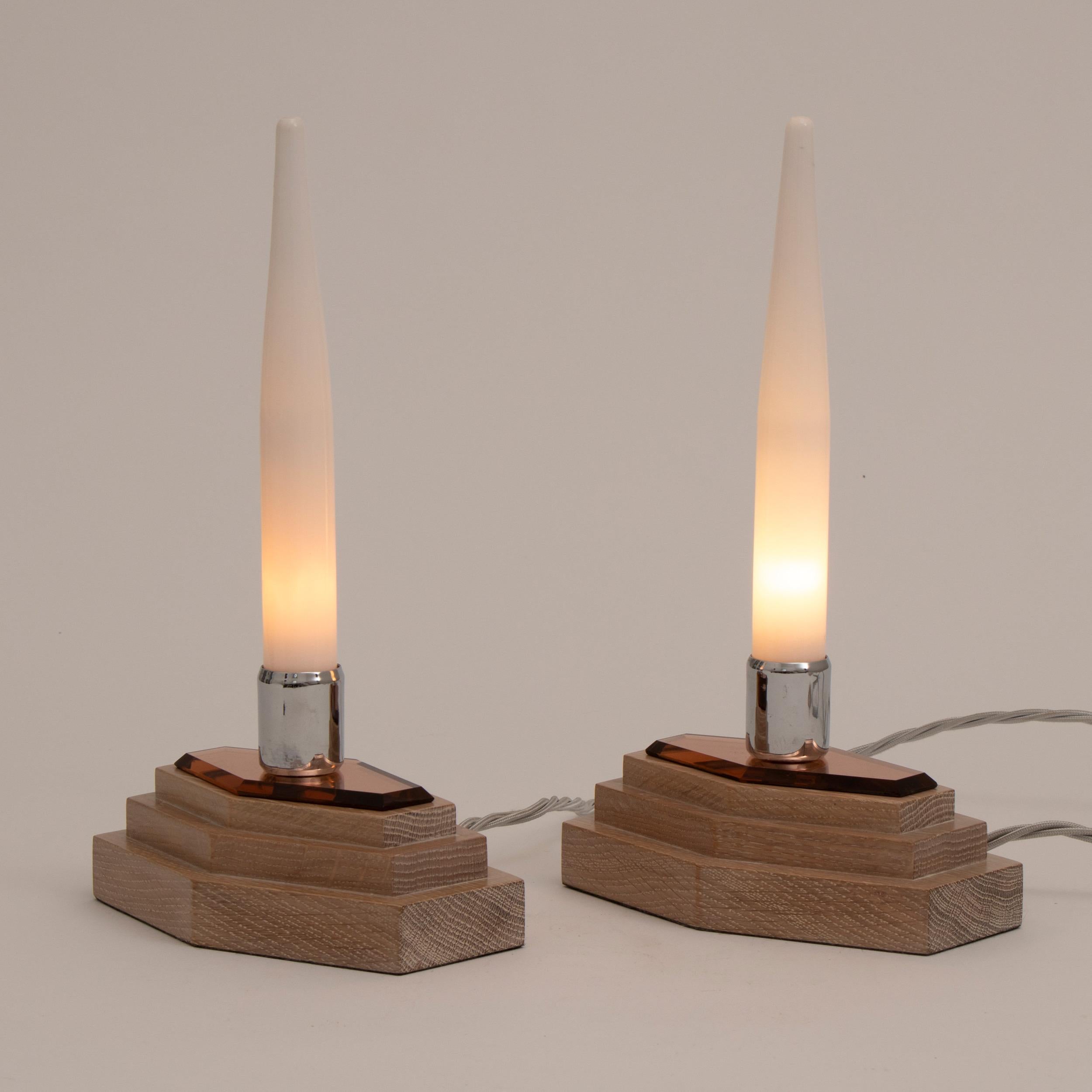 A smart pair of modernist Art Deco candle lights on stepped polished limed oak base with beveled peach mirror glass tops. Topped with a candle shaped opal glass shade with a chrome sconce by Heals Tottenham court road London, circa 1930.
Measures: