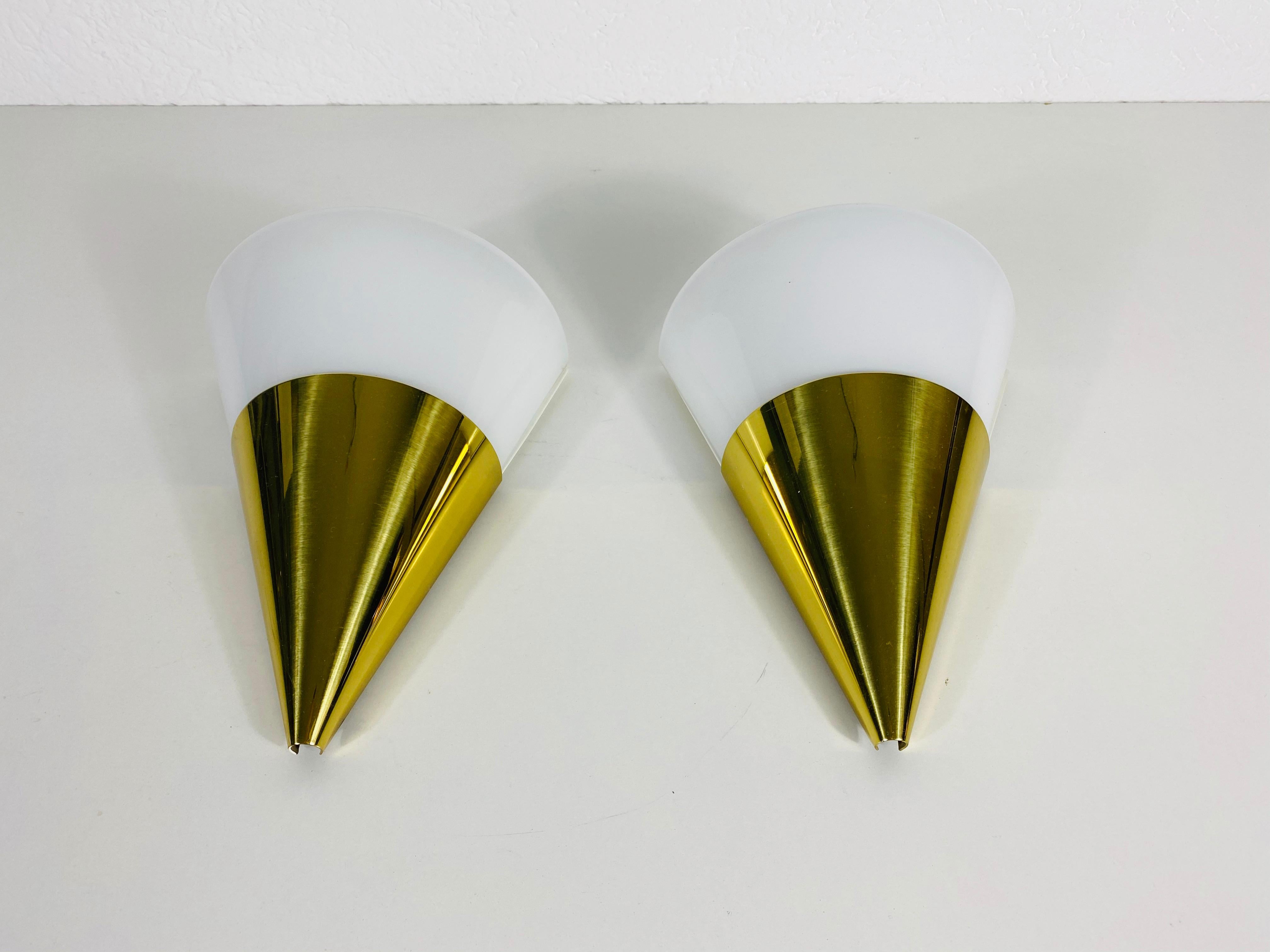 A beautiful pair of modern wall lamps by Glashütte Limburg made in Germany in the 1980s. They have a cone shape and are made of brass and Opaline glass. The back is made of metal.

The lightings require E14 light bulbs and work with both 120V and
