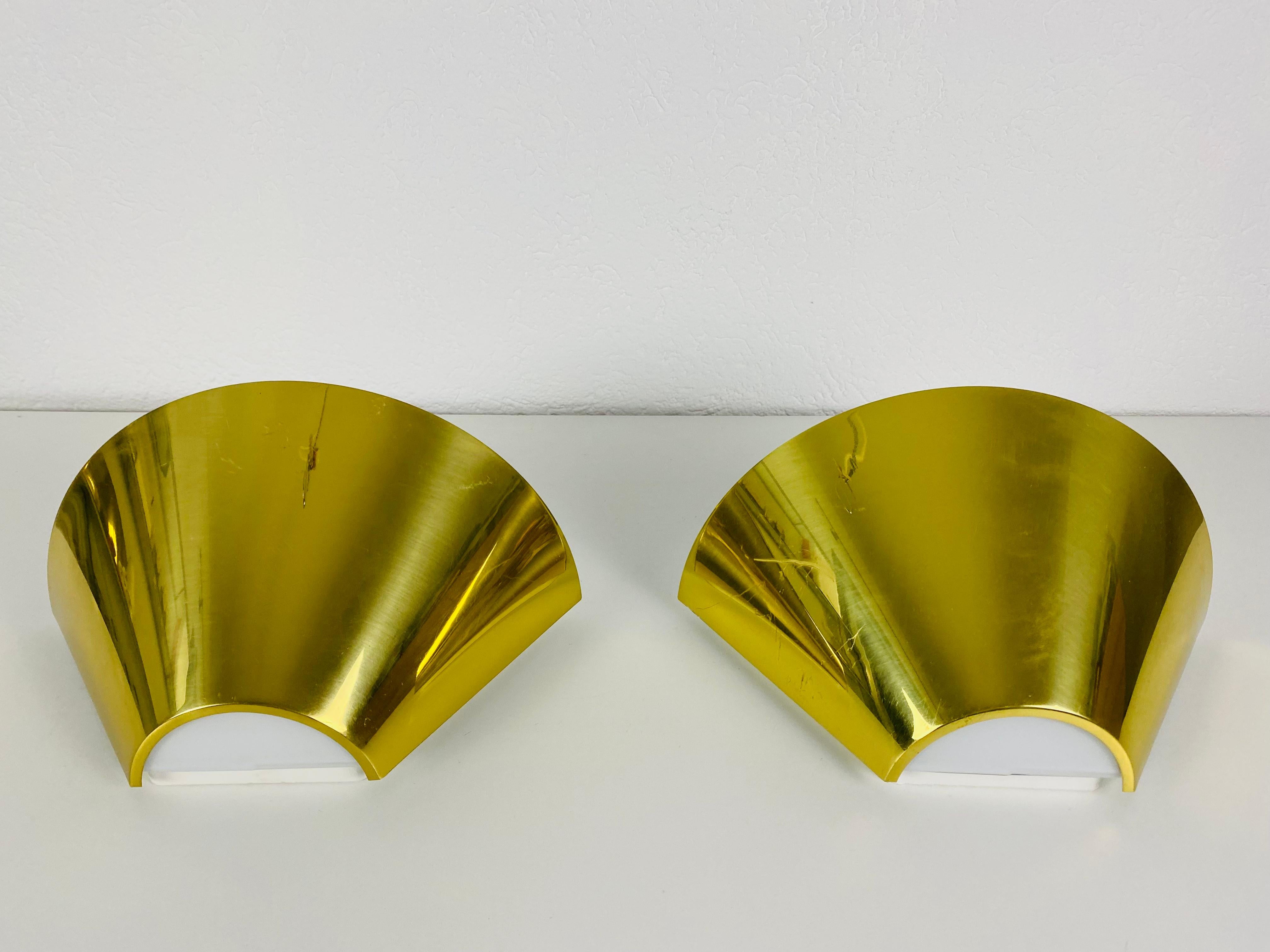 A beautiful pair of modern wall lamps by Glashütte Limburg made in Germany in the 1980s. They have a cone shape and are made of brass and opaline glass. The back is made of metal.

The lightings work with both 120V and 220V. Very good vintage