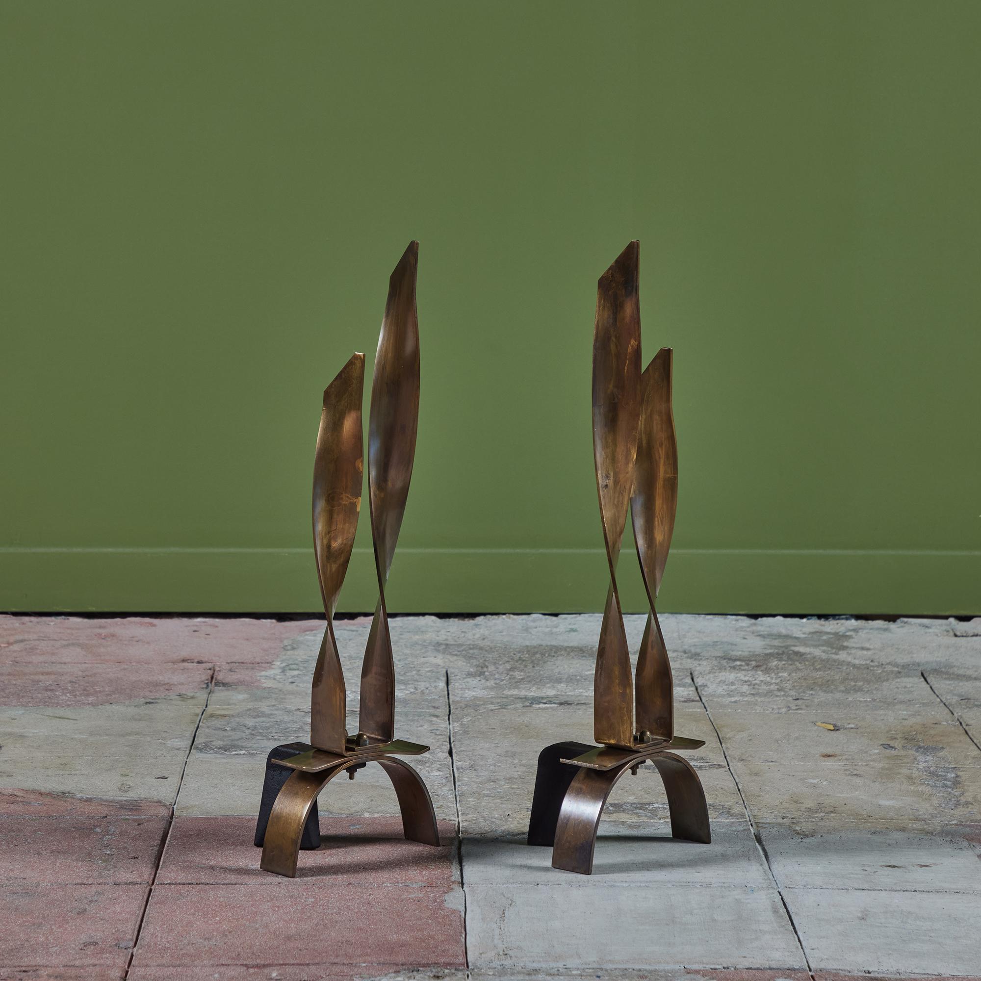 Pair of brass andirons. The andirons feature two ribbon like twisted fronts with varied heights with a curved base. 

Dimensions
7.25