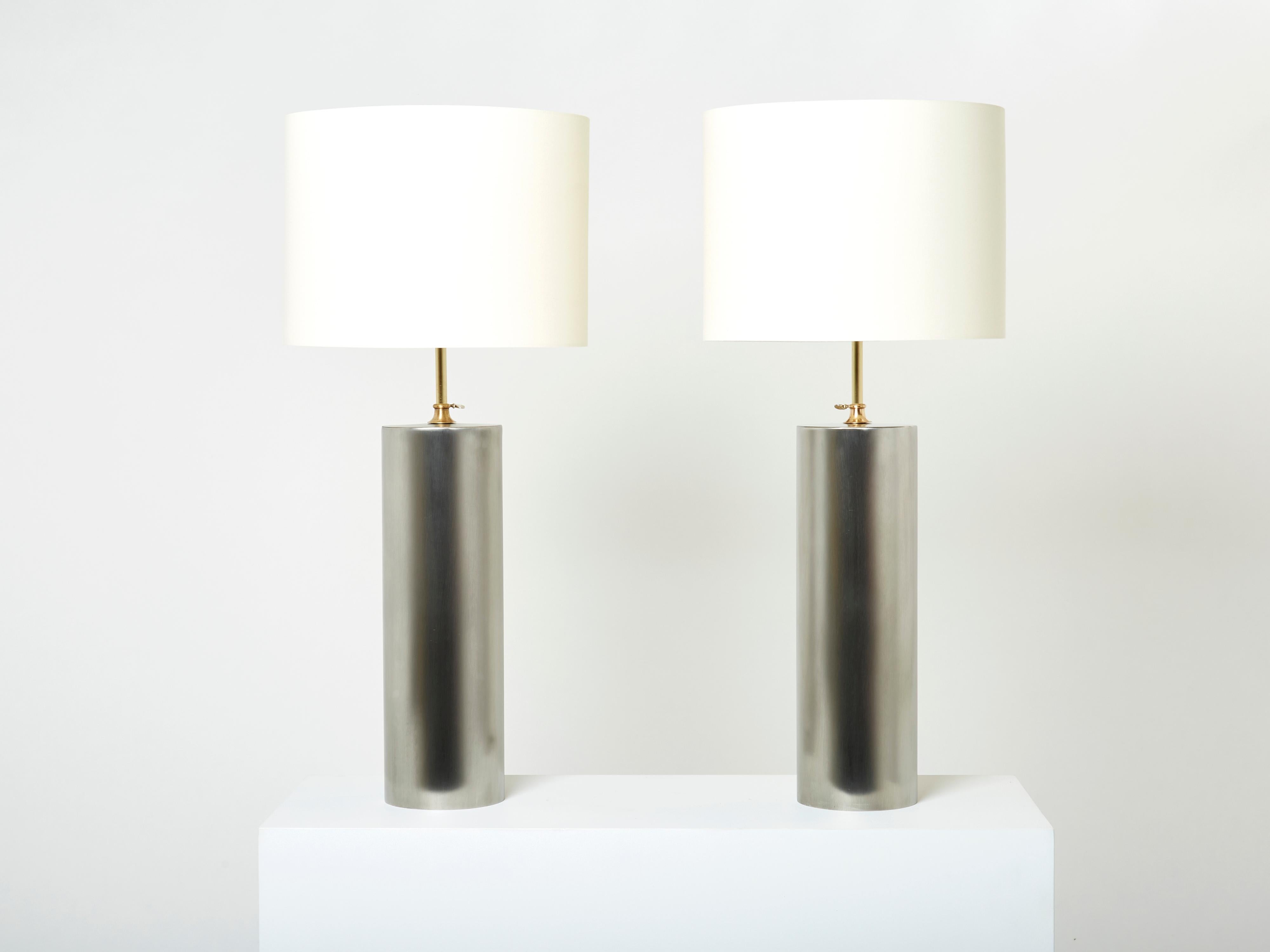 This elegant pair of table lamps is sure to add an element of French modernism chic to any room. It was designed and produced in the late 1960s. With a cylinder brushed steel base and brass adjustable height mounting, these tables are a wonderful
