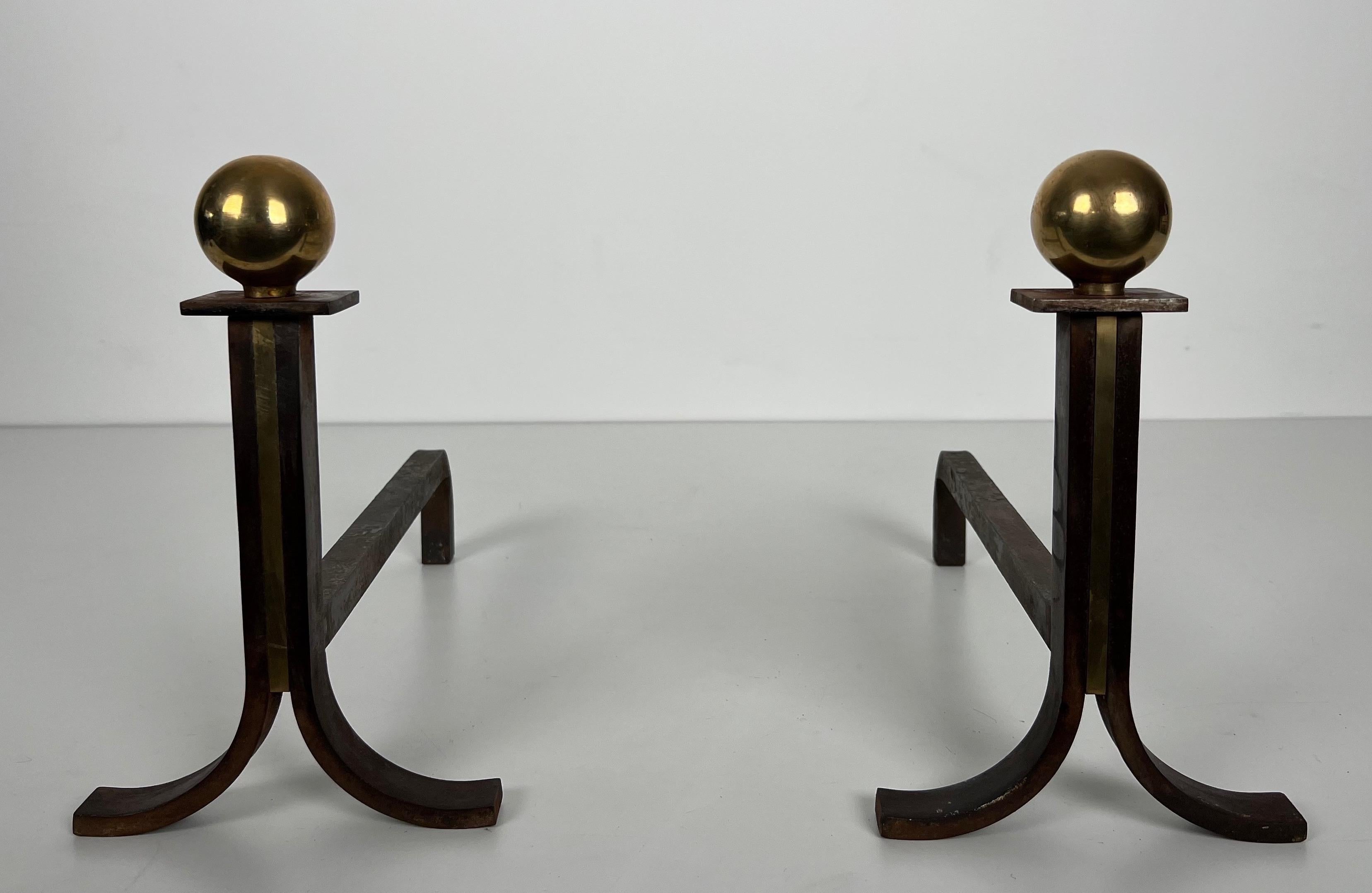 This very nice and elegant pair of modernist andirons is made of steel, brass and wrought iron. This is a French work in the style of Jacques Adnet. Circa 1940