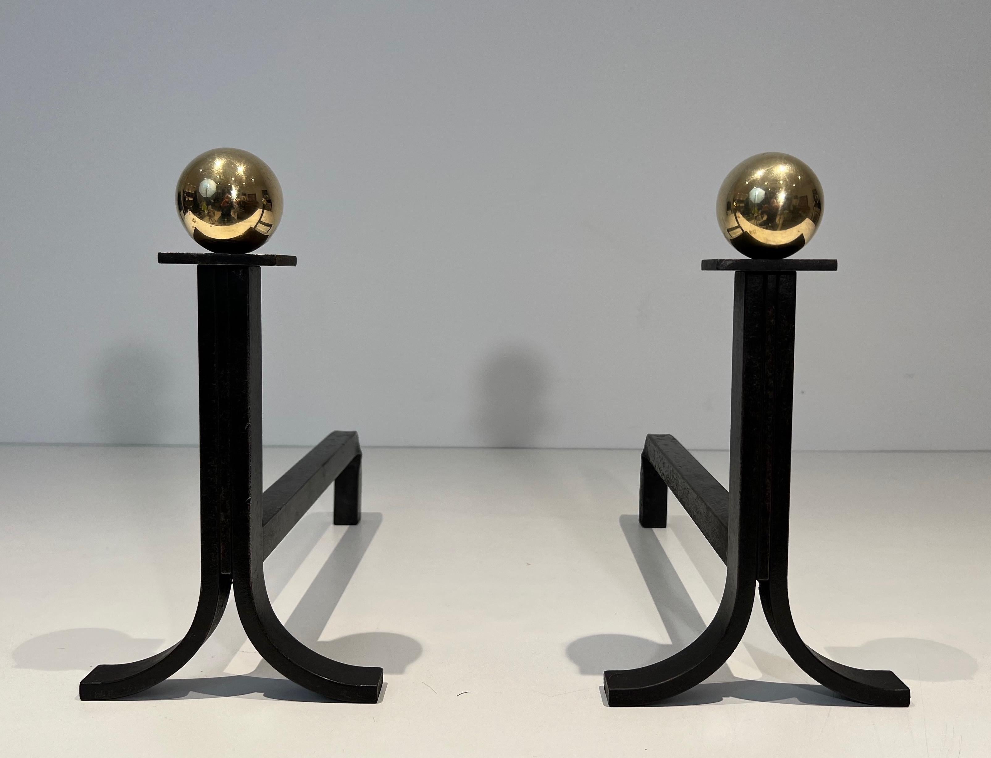 This nice pair of modernist andirons is made of wrought iron, brass and cast iron. This is a French work in the style of Jacques Adnet. Circa 1940