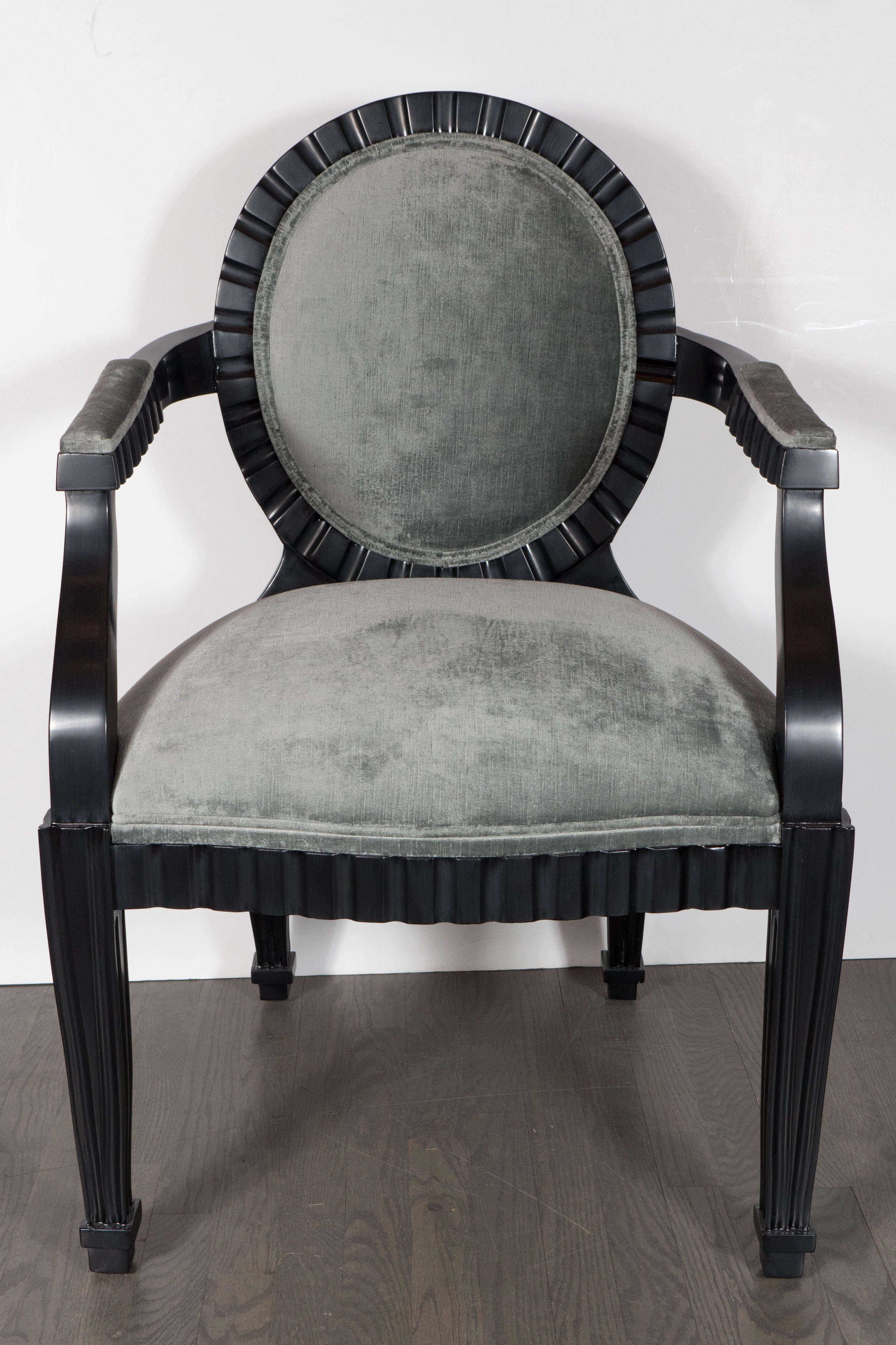 This stunning pair of modernist chairs were realized by the esteemed designer Donghia in the United States, circa 1980. They feature ebonized walnut bodies with circular backs, conical legs and scalloped channel detailing that runs around the border
