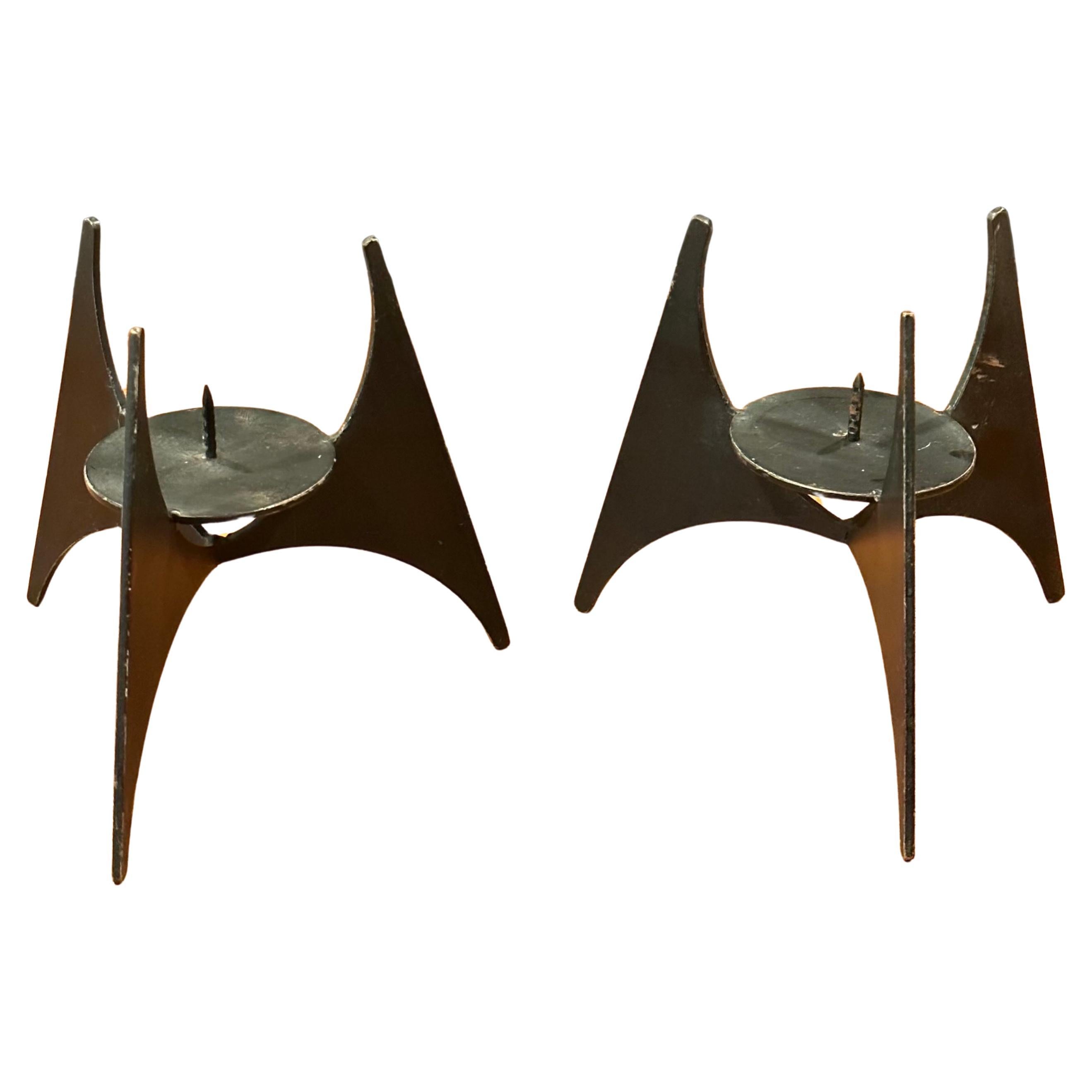 Ein schönes Paar modernistischer Kerzenhalter aus Stahl, circa 1970er Jahre.   Der Halter hat die Form einer dreieckigen Pyramide, die von einem dreibeinigen Sockel getragen wird und bis zu einer Kerze mit einem Durchmesser von 3