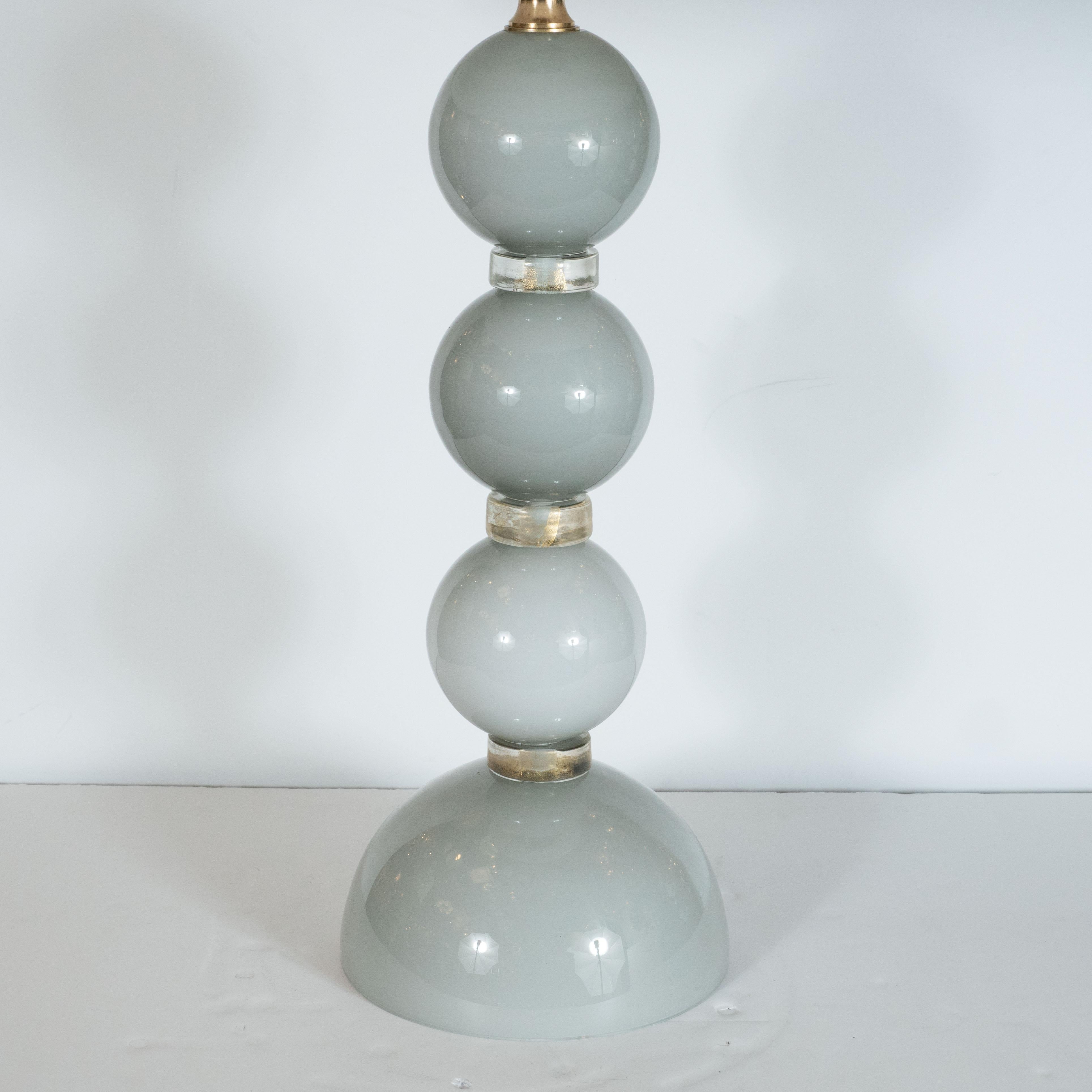 This elegant pair of table lamps were hand blown in Murano, Italy- the islands off the coast of Venice centuries renowned for superlative glass production. Each lamp has three vertically stacked, identical dove grey colored glass spheres which rest