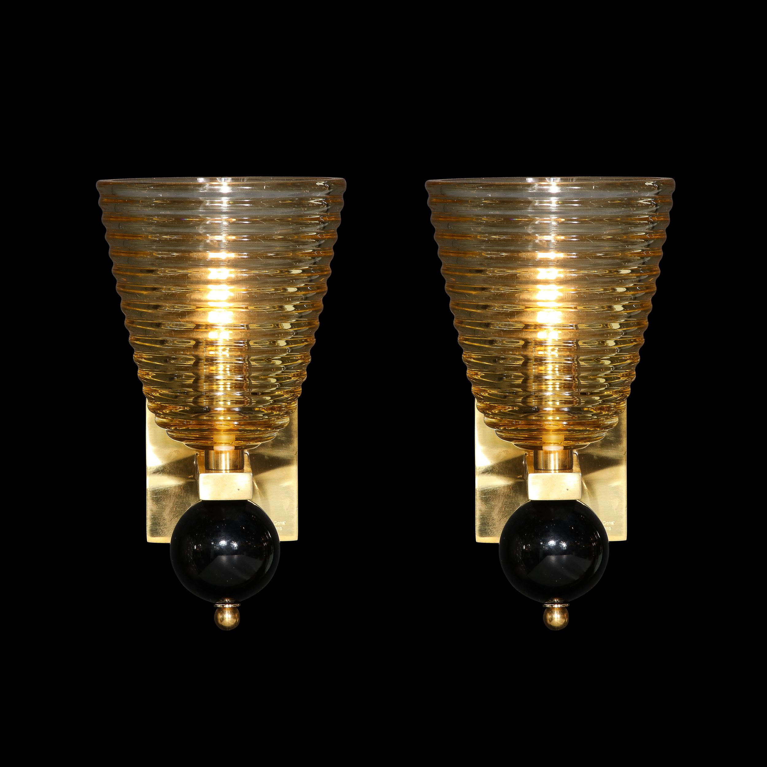 This stunning and graphic pair of modernist sconces were realized in Murano, Italy- the island off the coast of Venice renowned for centuries for its superlative glass production. They feature conical bodies with dramatically ribbed silhouettes that