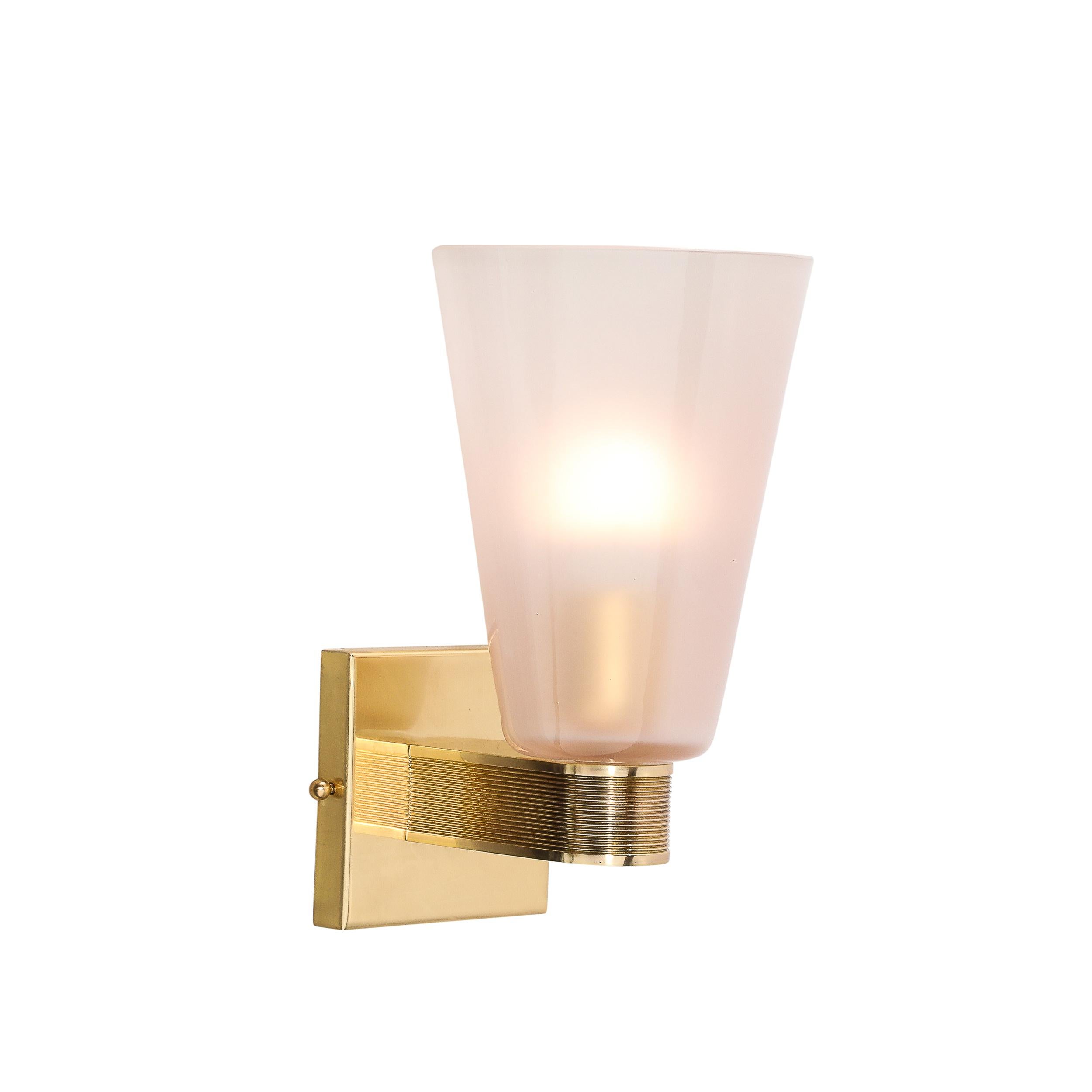 This elegantly minimal Pair of Modernist Hand-Blown Murano Glass Sconces in Smoked Pink Garnet Hue W/ Reeded Brass Fittings originates from Italy during the 21st Century. Featuring a conical profile in hand-blown murano glass sporting a subtle yet