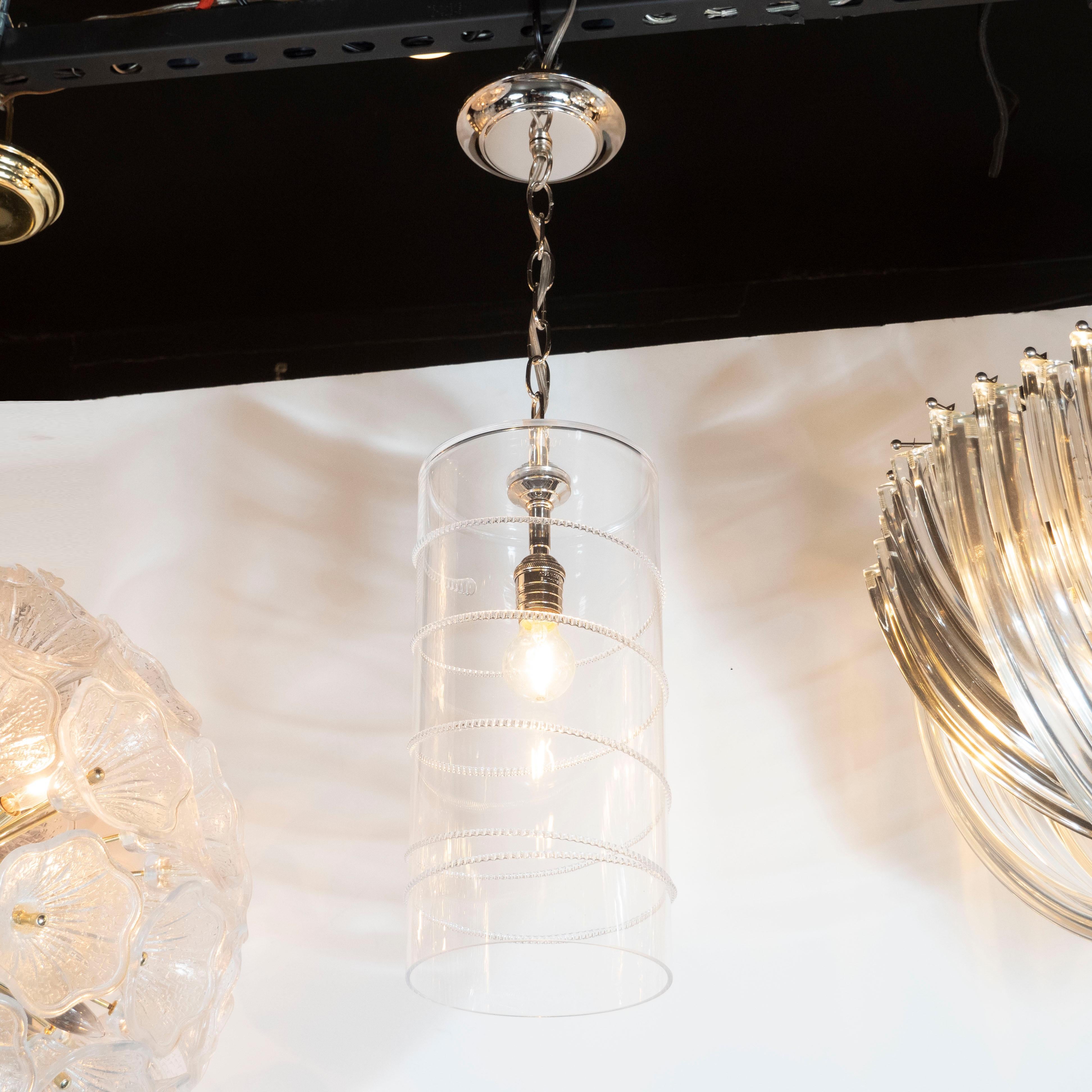 This sophisticated pair of modernist pendants offer a hand blown cylindrical form with a helix form pattern of beaded glass running along the exterior in relief. They attach to the ceiling via a nickel chain and canopy. With their clean modernist