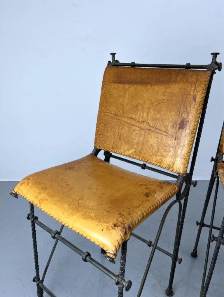 Pair of European Modernist iron and rebar frame stools with distressed original tan leather backrests and seats. Stains and water spots to leather as shown; border stitching details in good condition. 