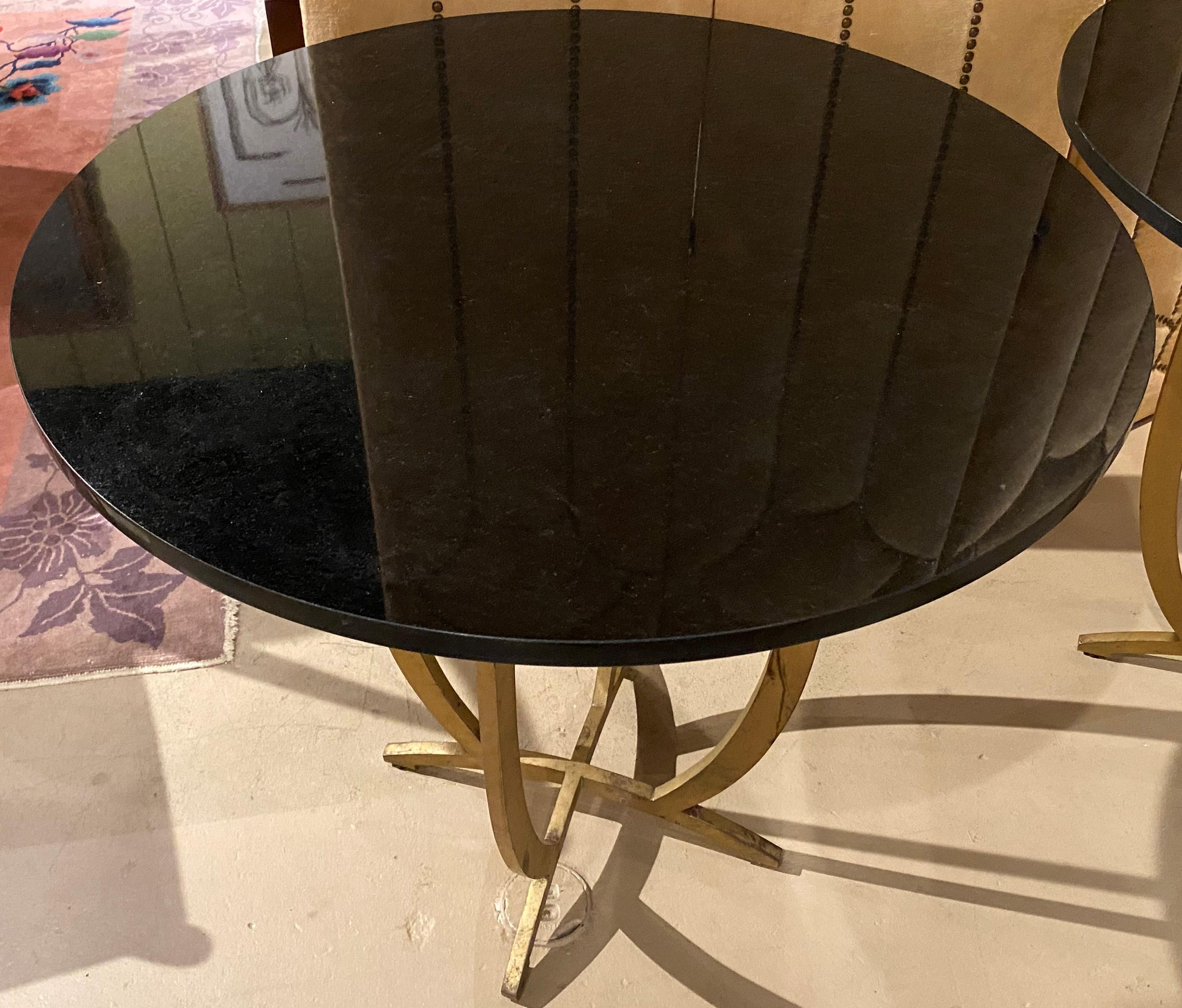Une paire de solides tables modernistes à plateau en marbre noir avec des bases élégantes en fer doré, en très bon état, avec quelques frottements de surface, des imperfections et une usure proportionnelle à l'âge et à l'utilisation. La paire date