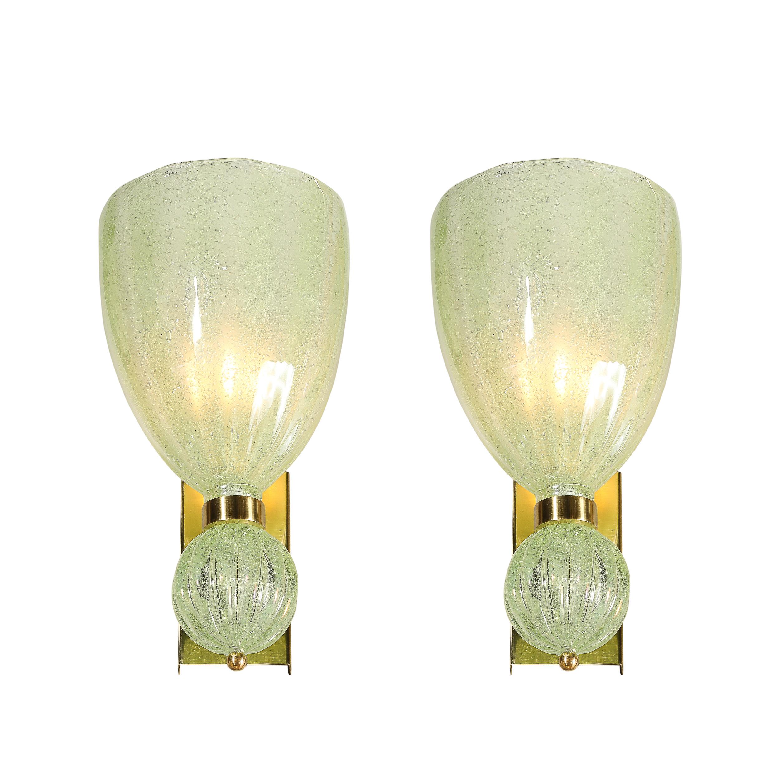 This elegant pair of modernist hand-blown Murano glass sconces, crafted in Italy in the 21st century, features a delightful pale jade green hue that brings a serene touch to any room. The beautifully formed glass is complemented by brass fittings,