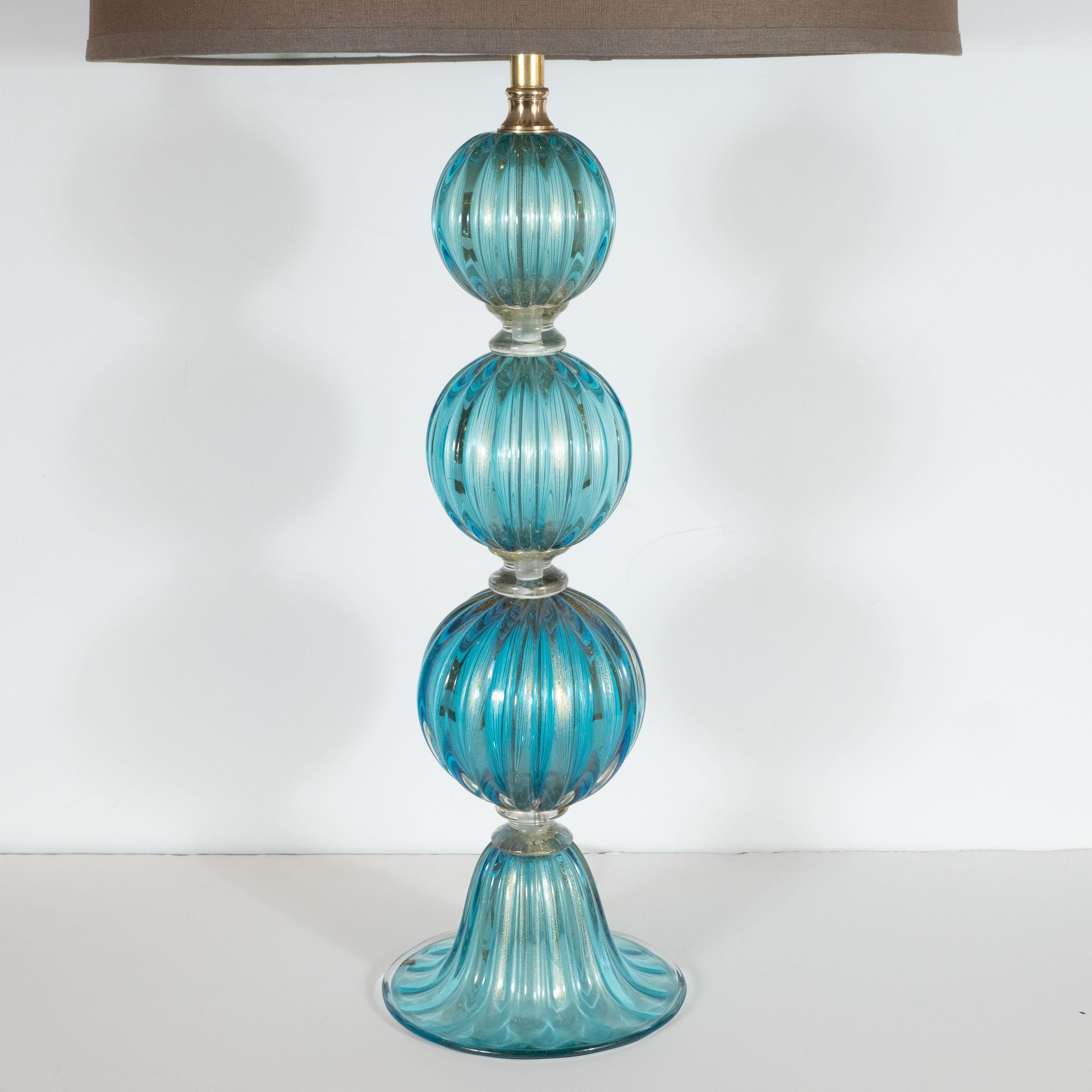 This sophisticated pair of modernist table lamps were hand blown in Murano, Italy, the island off the coast of Venice renowned for centuries for its superlative glass production. It features three ribbed orbital forms ascending from a gently concave