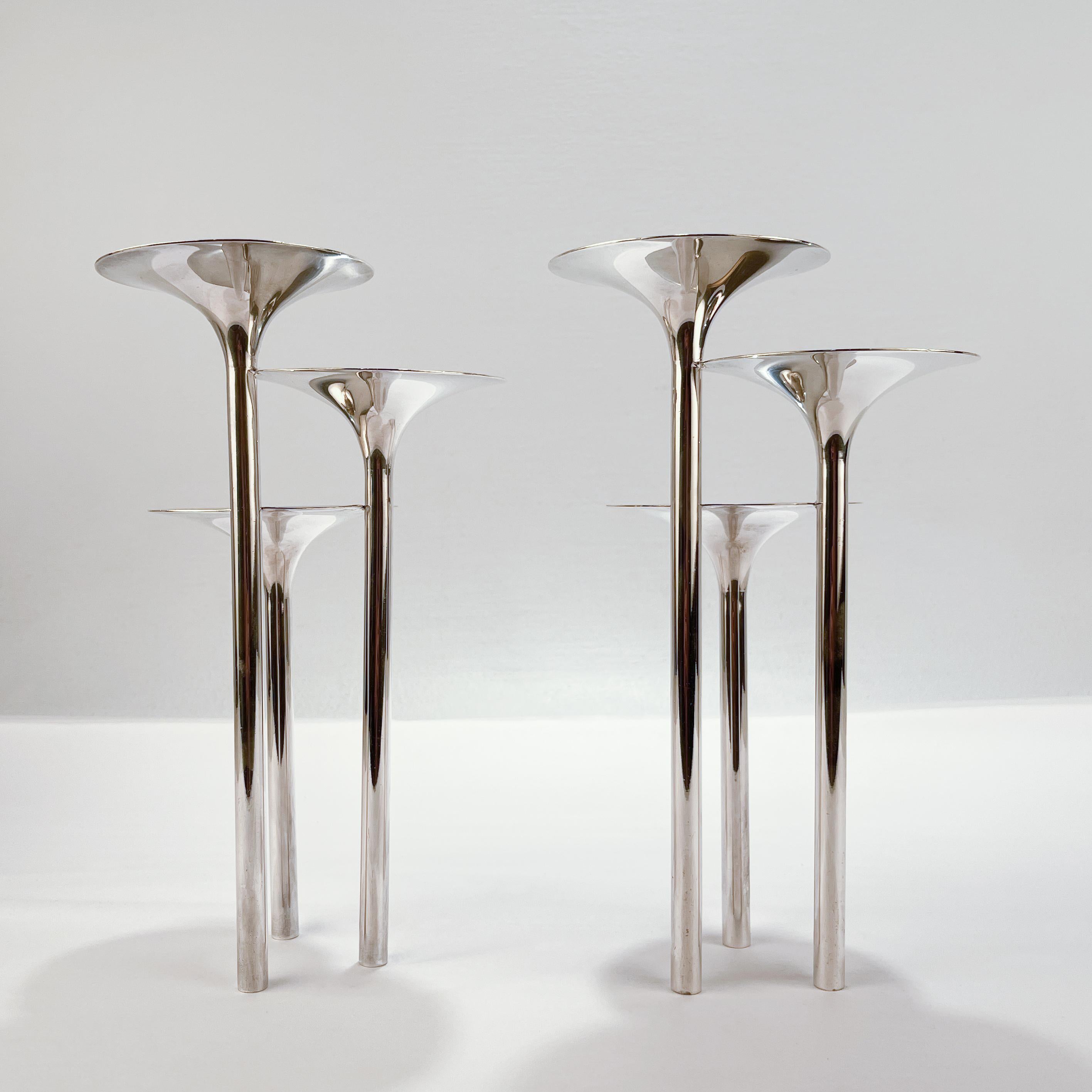 A fine pair of Modernist Christofle candle holders.

Entitled 'Concerto di Trombe'.

Designed by Lino Sabattini for the Gallia division of Christofle in 1959.

Each modeled as 3 trumpet form vessels joined at their stems.

(Because they are