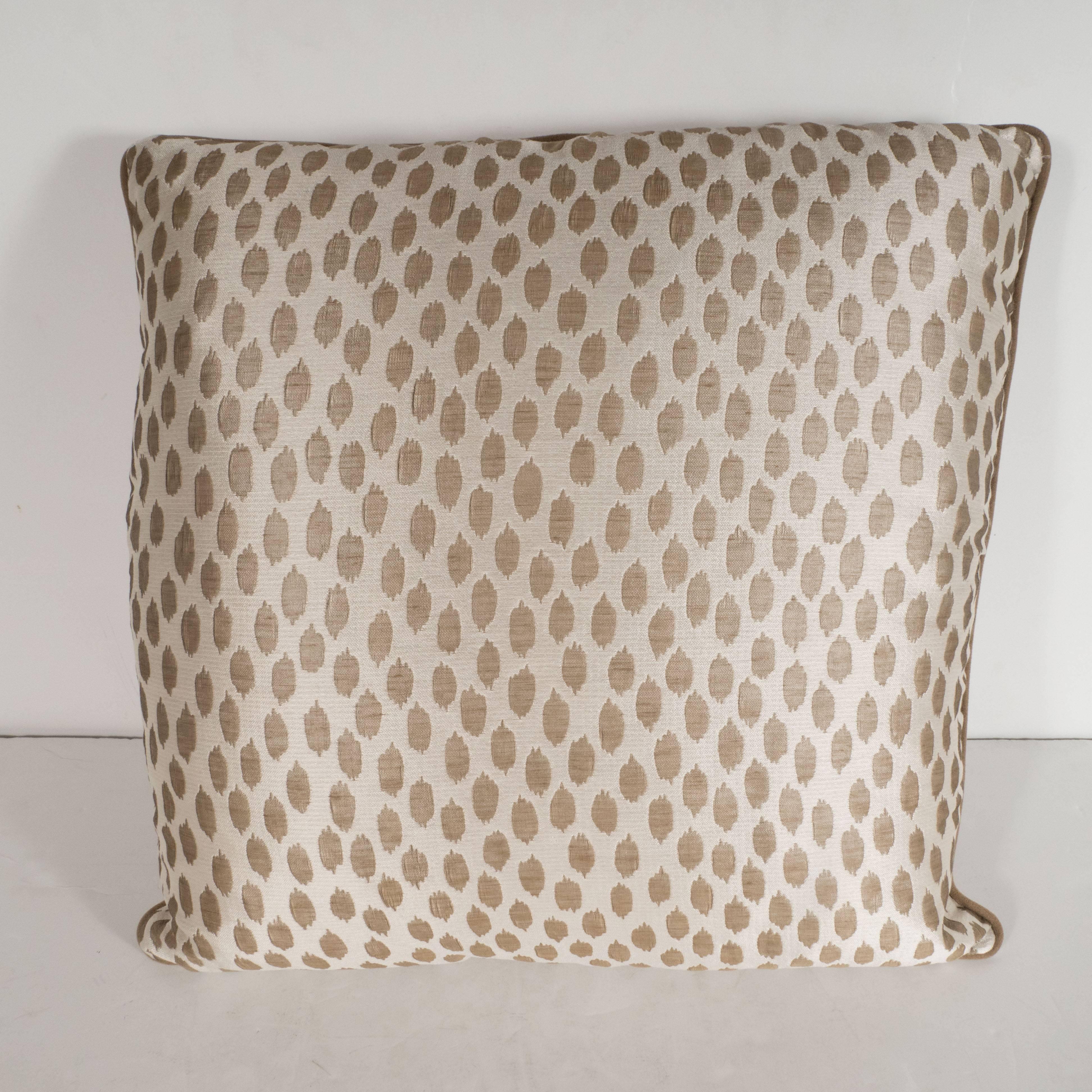 This elegant pair of square modernist pillows features organic forms in muted gold hue- with piping in a matching tone- that float against an ecru background with a horizontal weave. With its austere form and sophisticated fabric, this pillow would