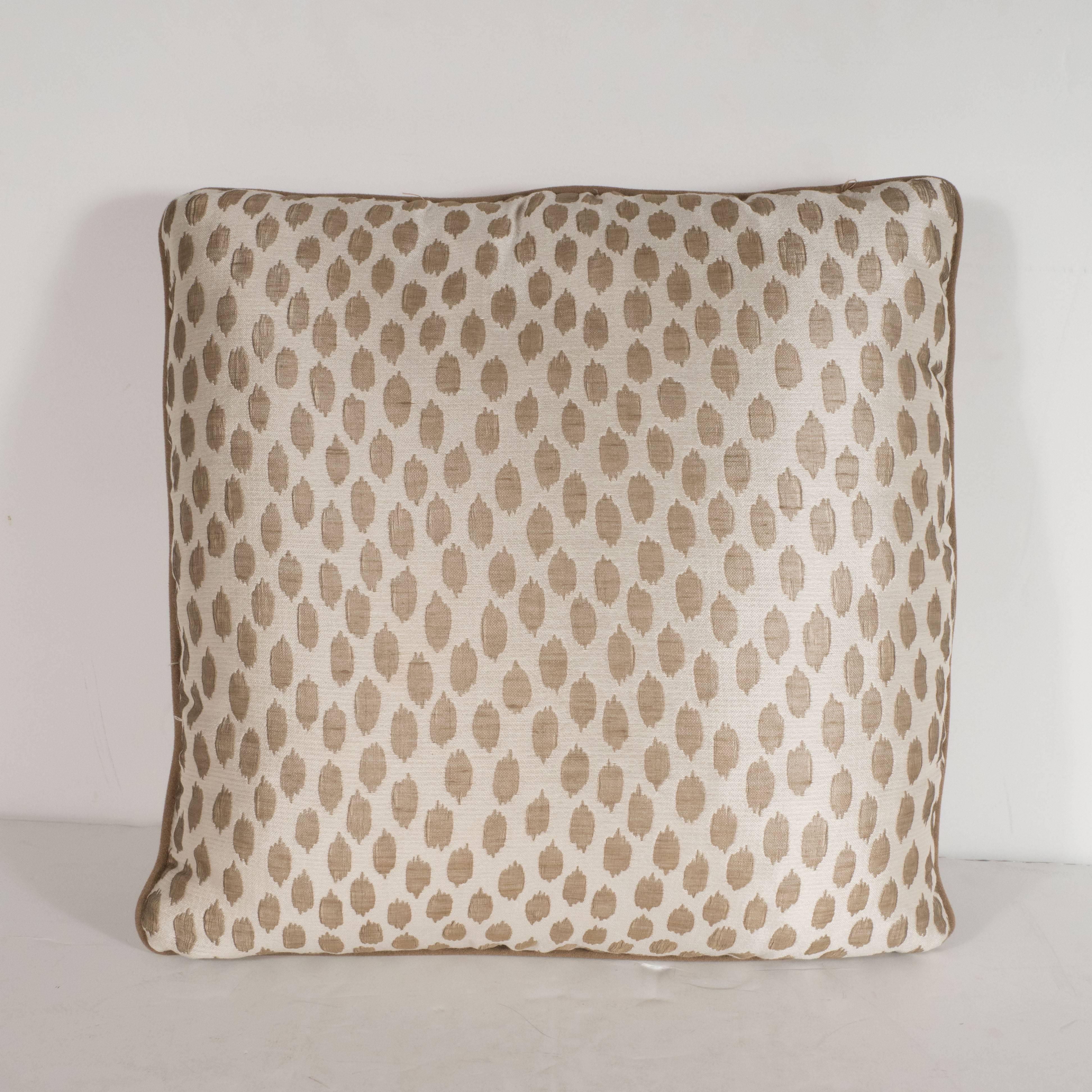 This elegant pair of square modernist pillows features organic forms in muted gold hue- with piping in a matching tone- that float against an ecru background with a horizontal weave. With its austere form and sophisticated fabric, this pillow would