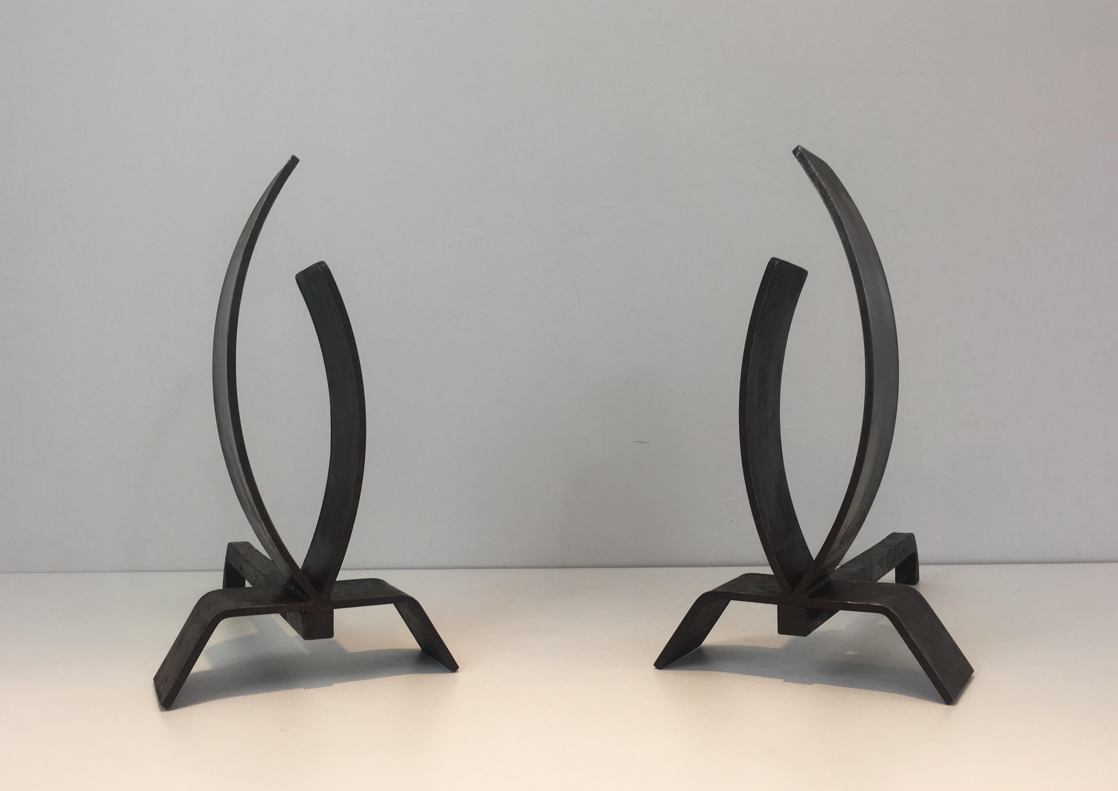 This pair of Modernist andirons are made of thick curved steel blades and iron. The design of these andirons is great and the quality really good, this is an interesting French work, circa 1970.