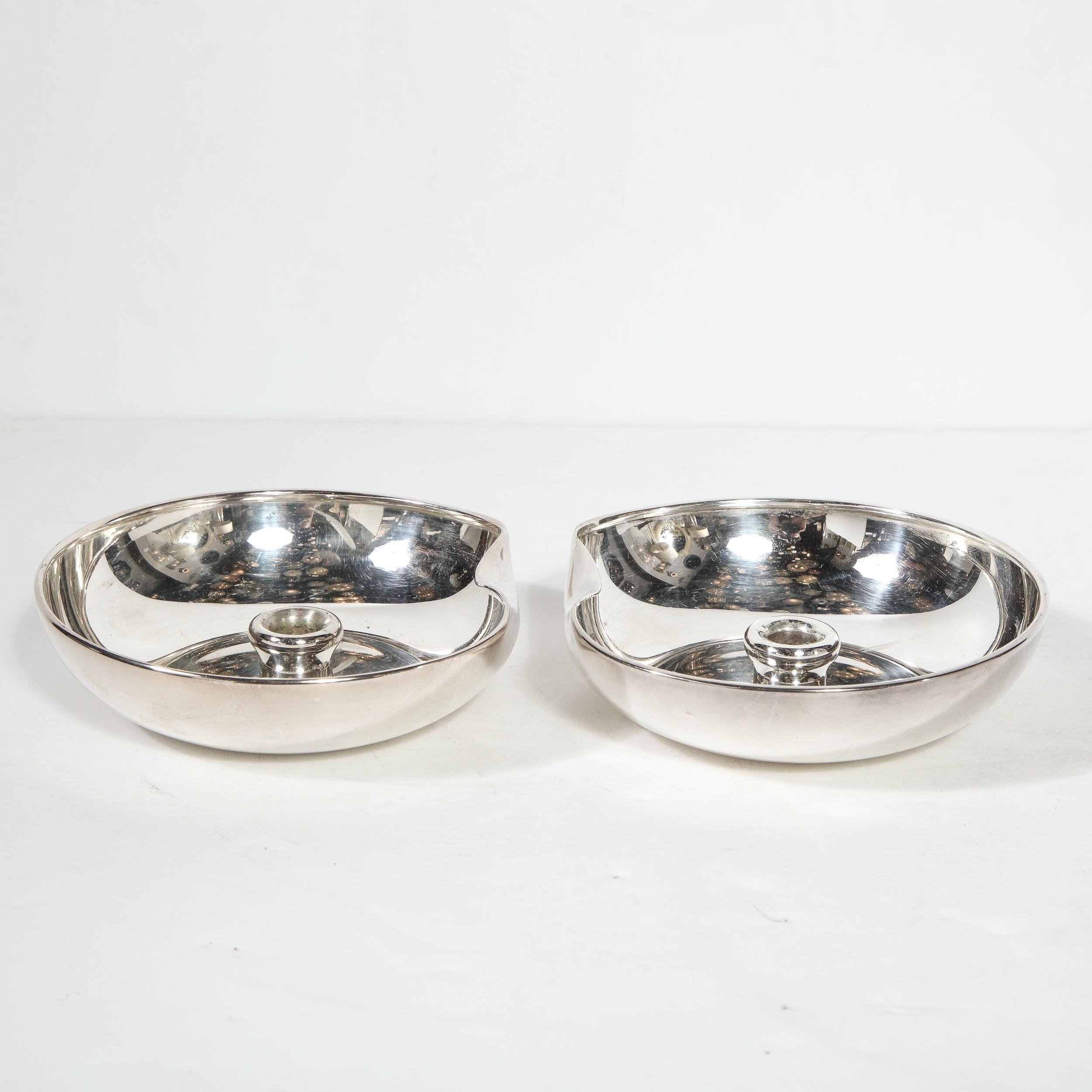 This stunning pair of Modernist sterling silver candle holders were realized by Elsa Peretti for Tiffany & Co, circa 1985. They feature circular bodies with curved raised sides and a sinuously curved depression on end of each candleholder. The