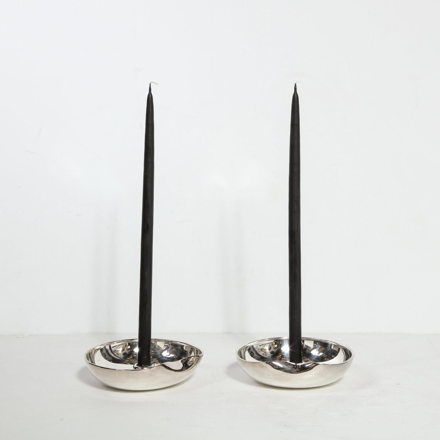 This stunning pair of Modernist sterling silver candle holders were realized by Elsa Peretti for Tiffany & Co, circa 1985. They feature circular bodies with curved raised sides and a sinuously curved depression on end of each candleholder. The