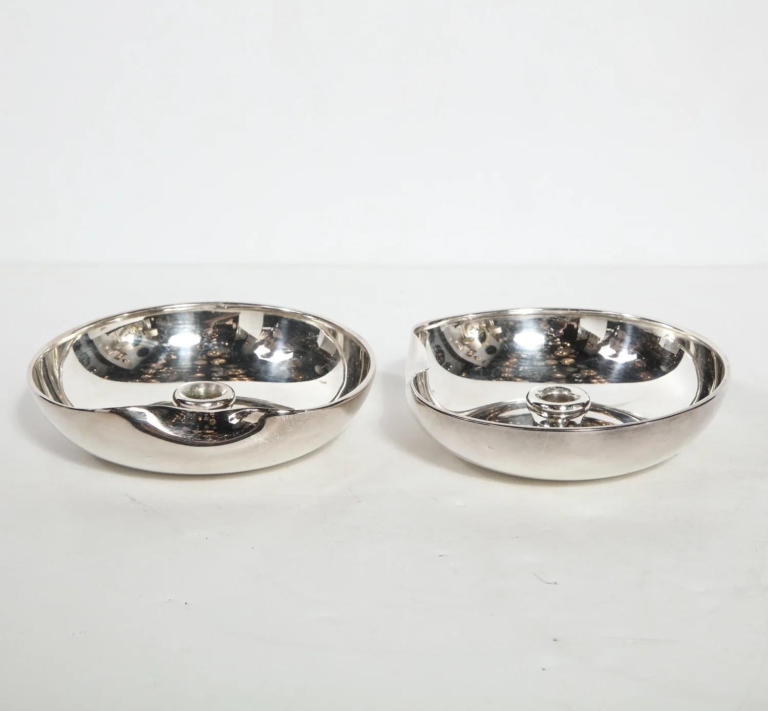 This stunning pair of Modernist sterling silver candle holders were realized by Elsa Peretti for Tiffany & Co, circa 1985. They feature circular bodies with curved raised sides and a sinuously curved depression on end of each candleholder. The